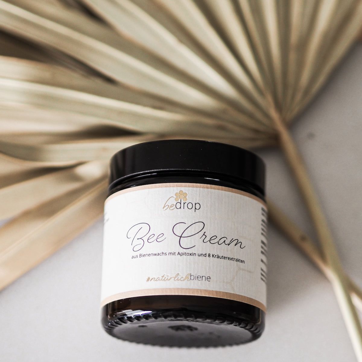 Braunes Glas mit Bee Cream-Etikett. Aufschrift: #natürlichbiene. Im Hintergrund ein getrocknetes Blatt.