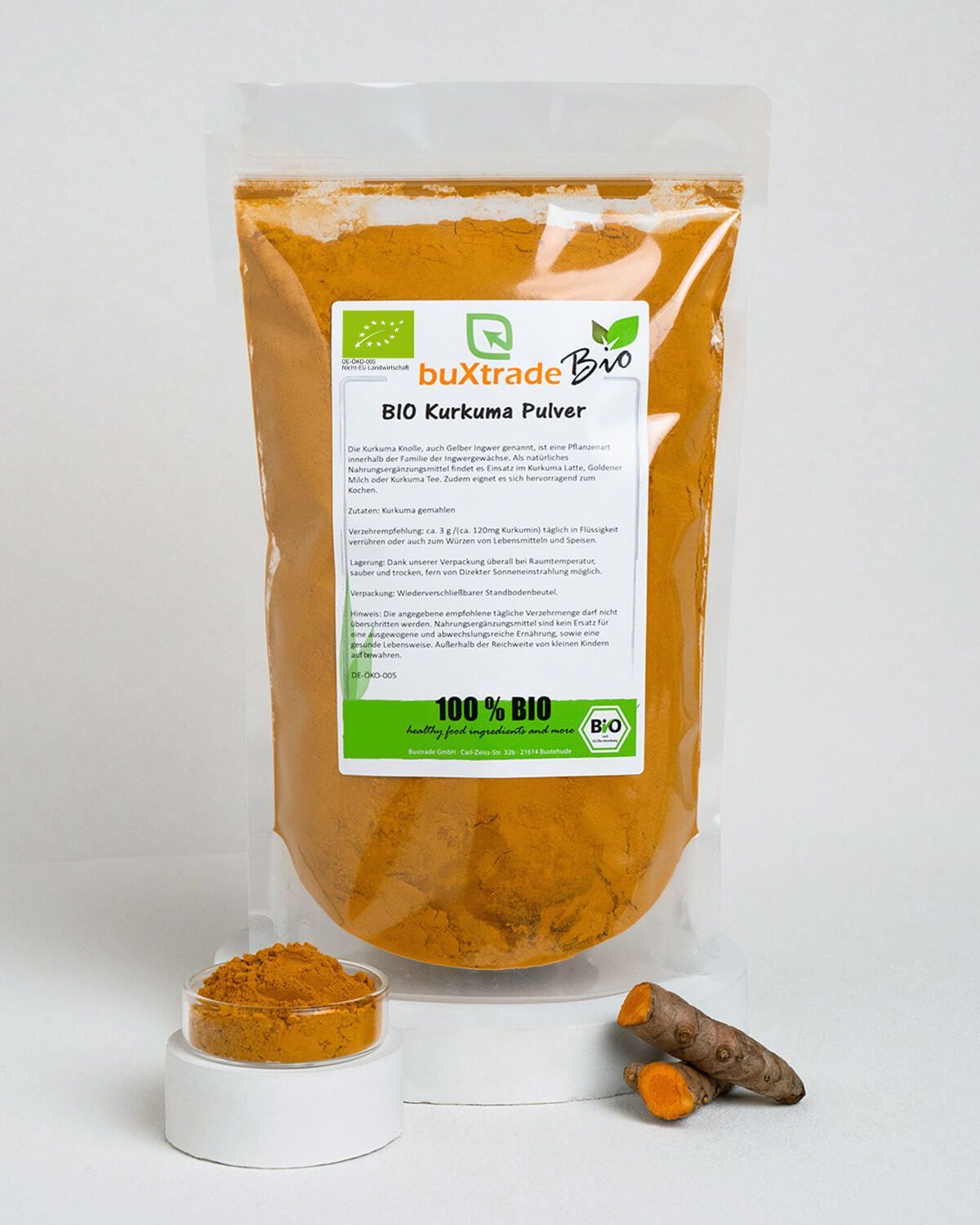 Verpackung mit BIO Kurkuma Pulver, daneben eine kleine Schale mit Pulver und zwei Kurkumastücke.