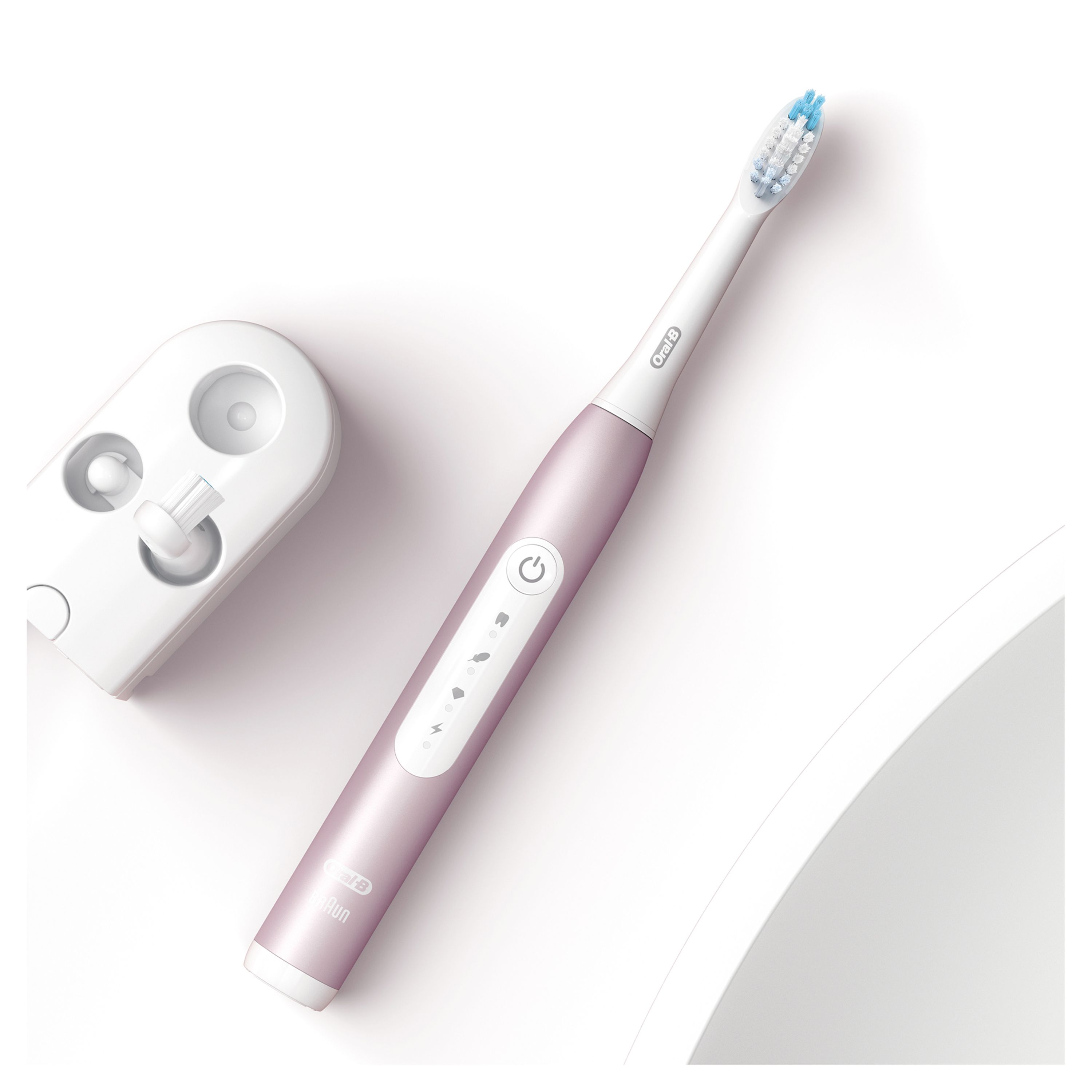 Elektrische Zahnbürste, Rosegold. Ladestation daneben. Oral-B Logo. Draufsicht.