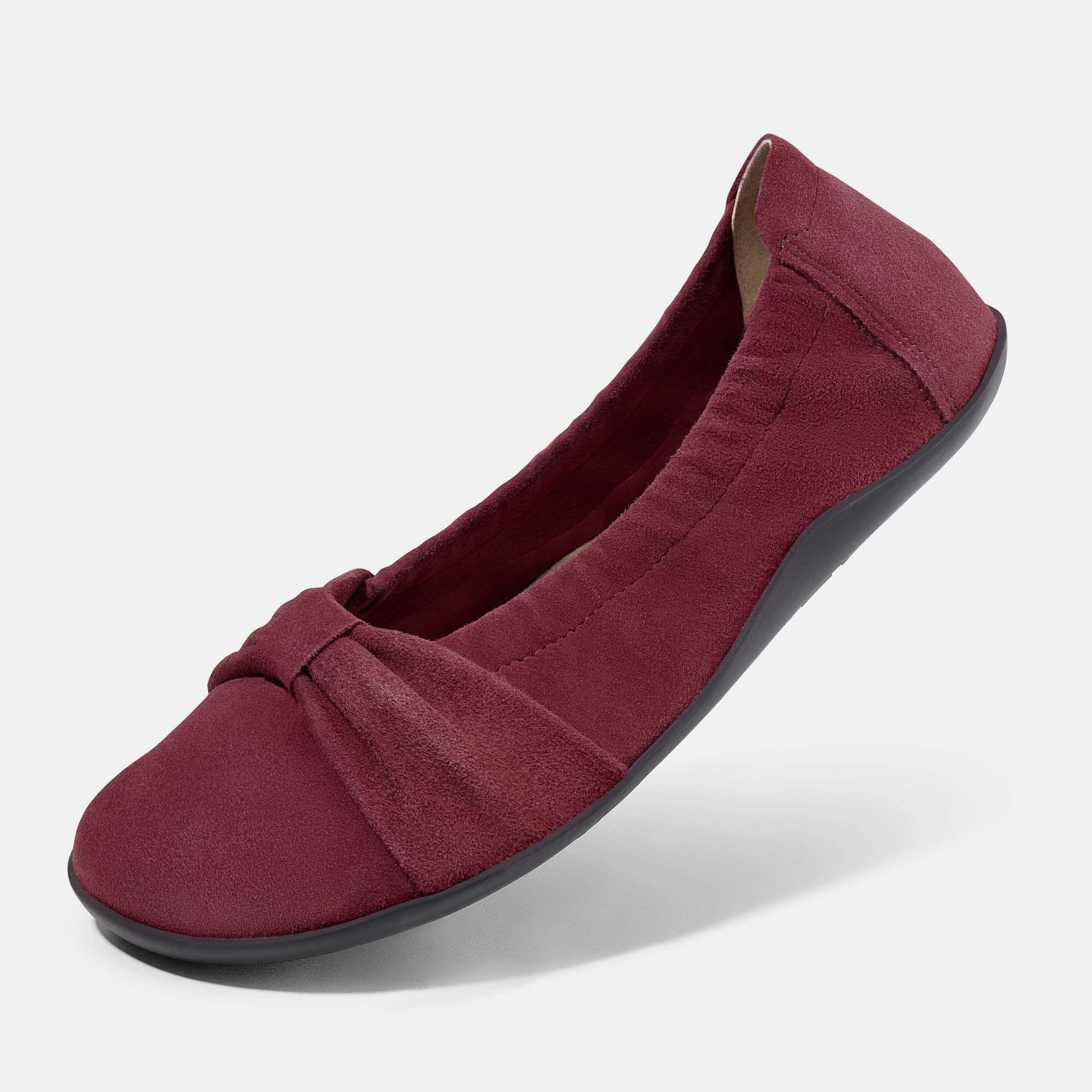 Eine bordeauxrote Ballerina aus Wildleder mit Schleifenverzierung, Gummisohle und elastischem Rand.