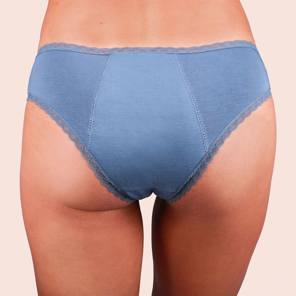 Blaue Periodenunterwäsche mit Spitze. Rückansicht, getragen von einer Person, auf hellem Hintergrund.