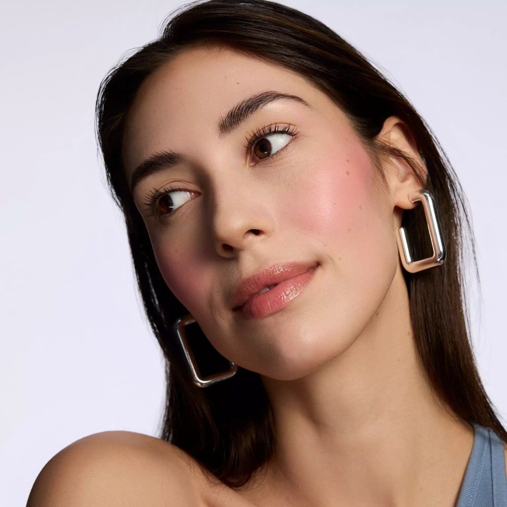 Porträt einer Frau mit Rouge auf den Wangen. Sie trägt Ohrringe.