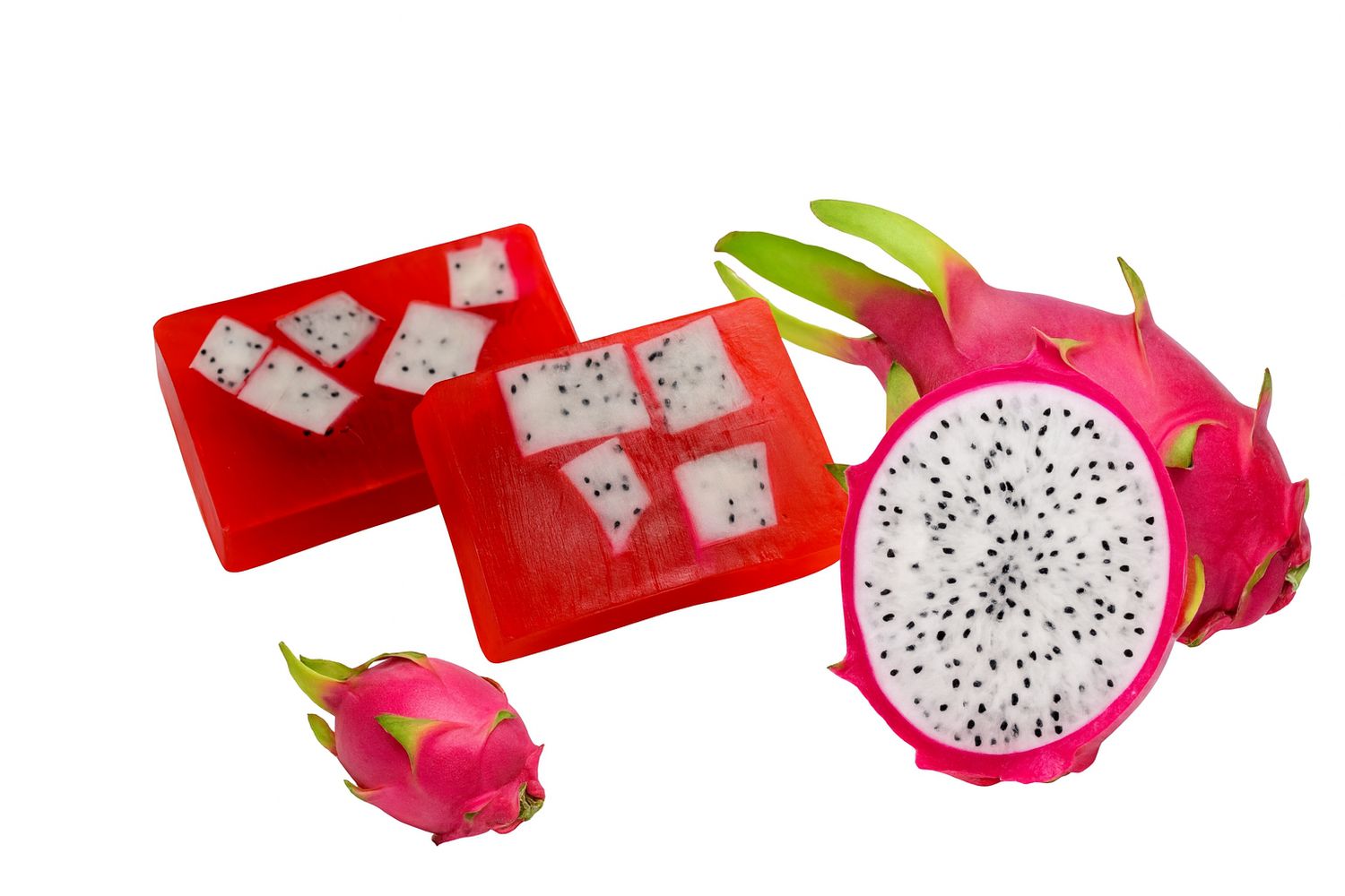 Rote Seifenstücke mit weißen Stücken, daneben Drachenfrüchte, eine angeschnitten. Auf weißem Hintergrund.
