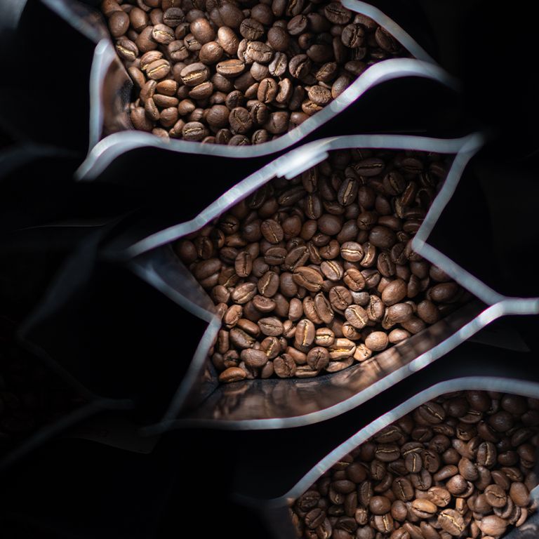 Kaffeebohnen in transparenten Beuteln. Nahaufnahme. Dunkler Hintergrund.