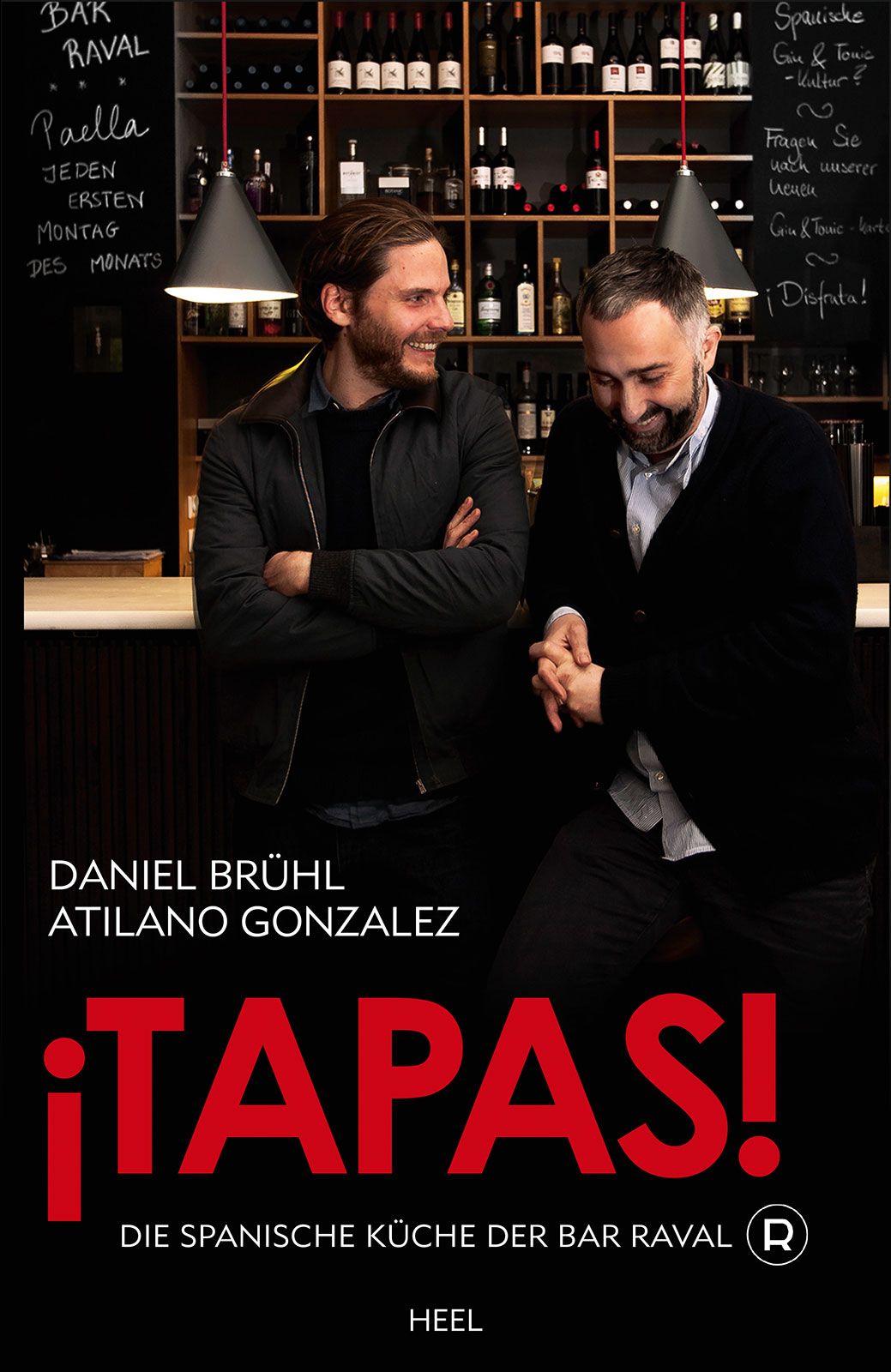 Buchcover: ¡TAPAS! Die spanische Küche der Bar Raval. Autoren: Daniel Brühl, Atilano Gonzalez. HEEL Verlag. Zwei Männer vor Bar.