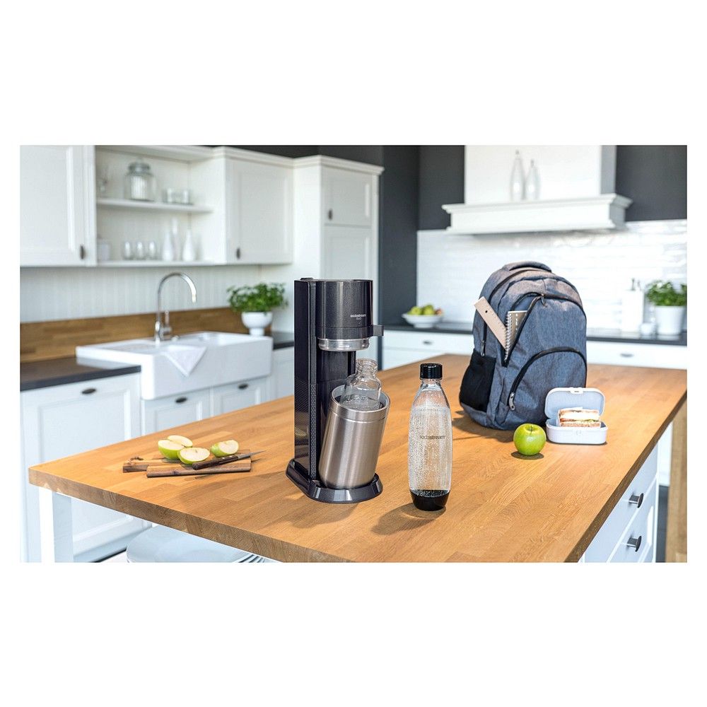 SodaStream Duo Wasseraufbereiter in einer Küche, neben einem Rucksack und Lebensmitteln.