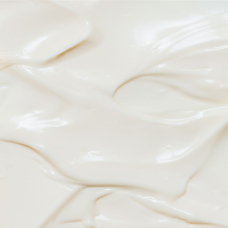 Nahaufnahme einer cremigen, weißen Substanz. Glatte, gewellte Textur.