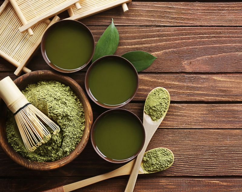 Holztisch mit Schalen, Matcha-Pulver und Zubehör. Enthält Matcha-Pulver, Schalen und Löffel.