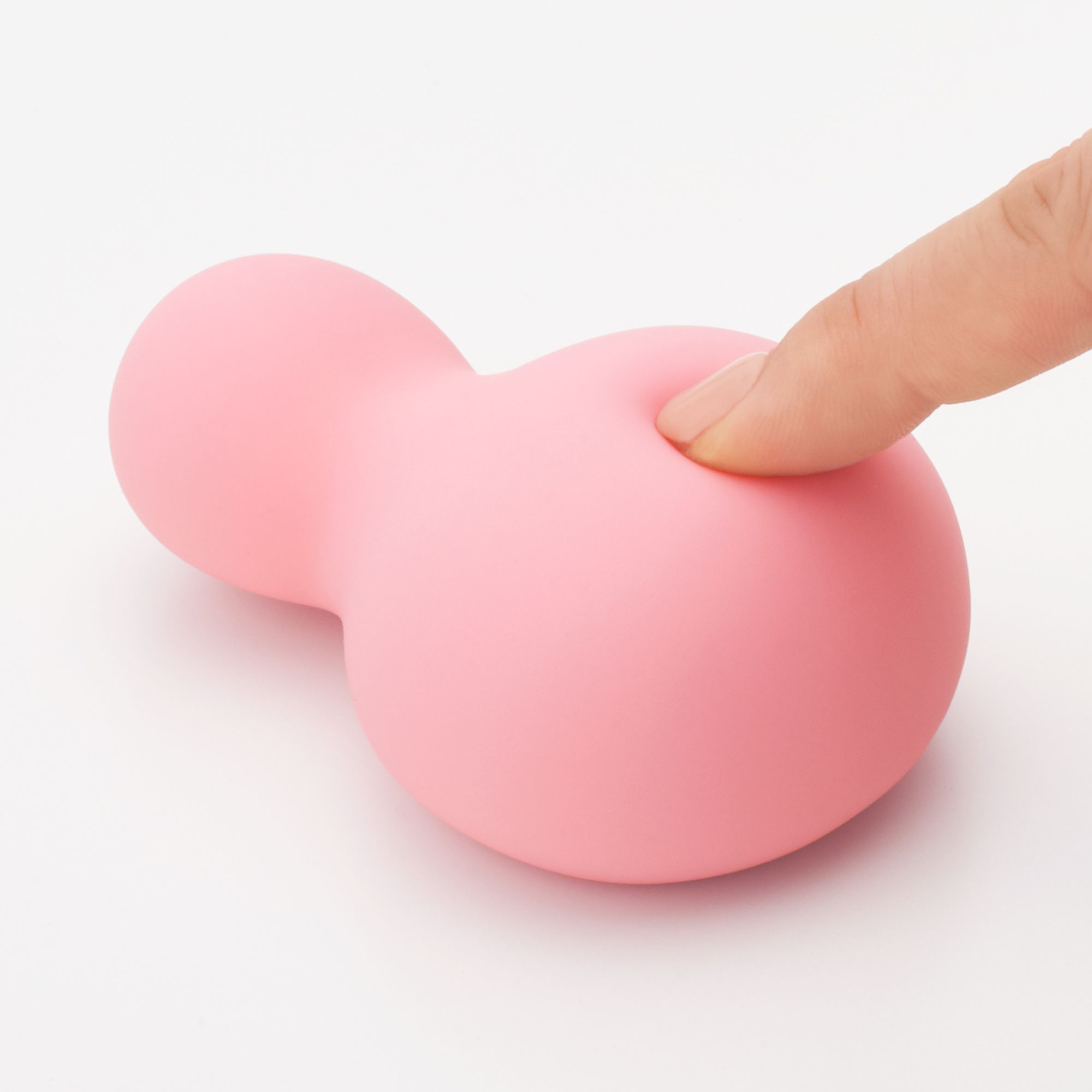 Rosa Produkt, Finger berührt die Oberfläche. Zwei abgerundete Teile. Glatte Oberfläche.