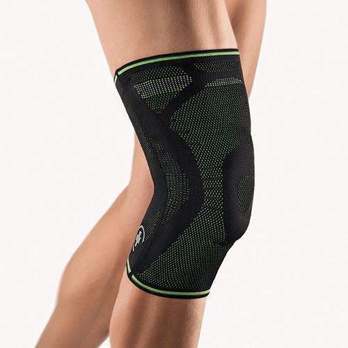 Schwarze Kniebandage am Bein. Grüne Akzente. Mesh-Material. Logo sichtbar.