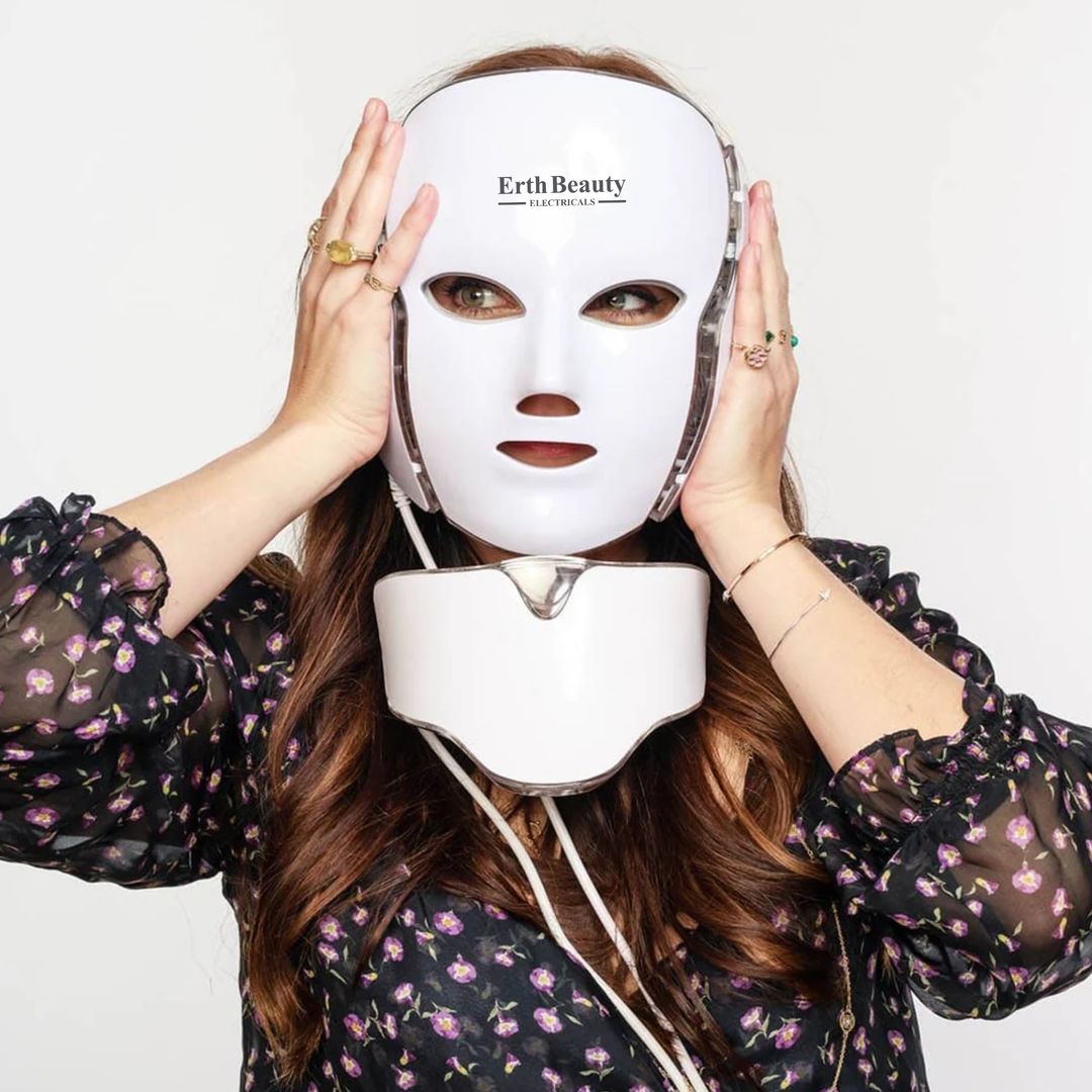 Eine Frau trägt eine weiße LED-Gesichtsmaske. Auf der Maske steht "Erth Beauty". Sie berührt die Maske mit den Händen.