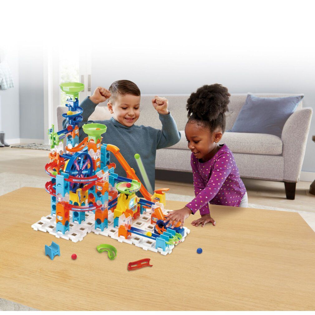 Kinder spielen mit VTech Marble Rush Ultimate Set. Bunte Konstruktion mit Bahnen, Trichter, Karussell.