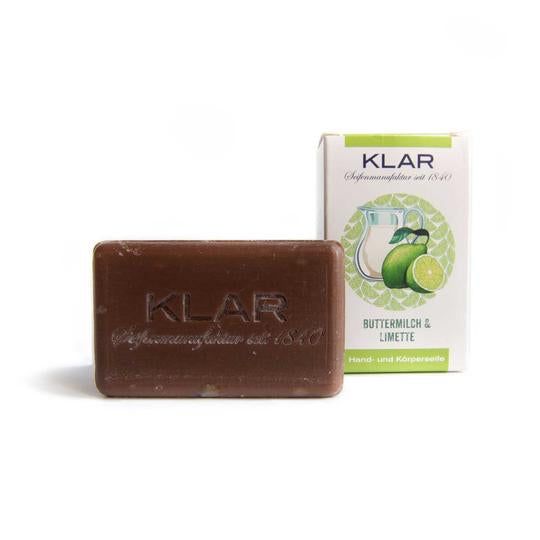 Braune Seife mit geprägtem Klar-Logo. Daneben die Verpackung mit Limetten-Illustrationen und Text: Buttermilch & Limette, Hand- und Körperseife.