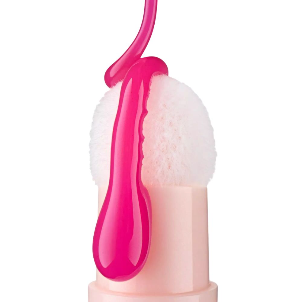 Ein rosa Applikator mit einem weißen, flauschigen Kopf, auf den eine dicke, glänzende rosa Flüssigkeit tropft.