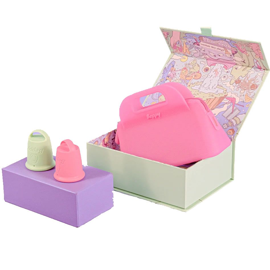 Hellgrüne und rosa Beppy Cups auf lila Block. Rosa Tasche in hellgrüner Box. Box mit Deckel, der mit bunten Illustrationen versehen ist.