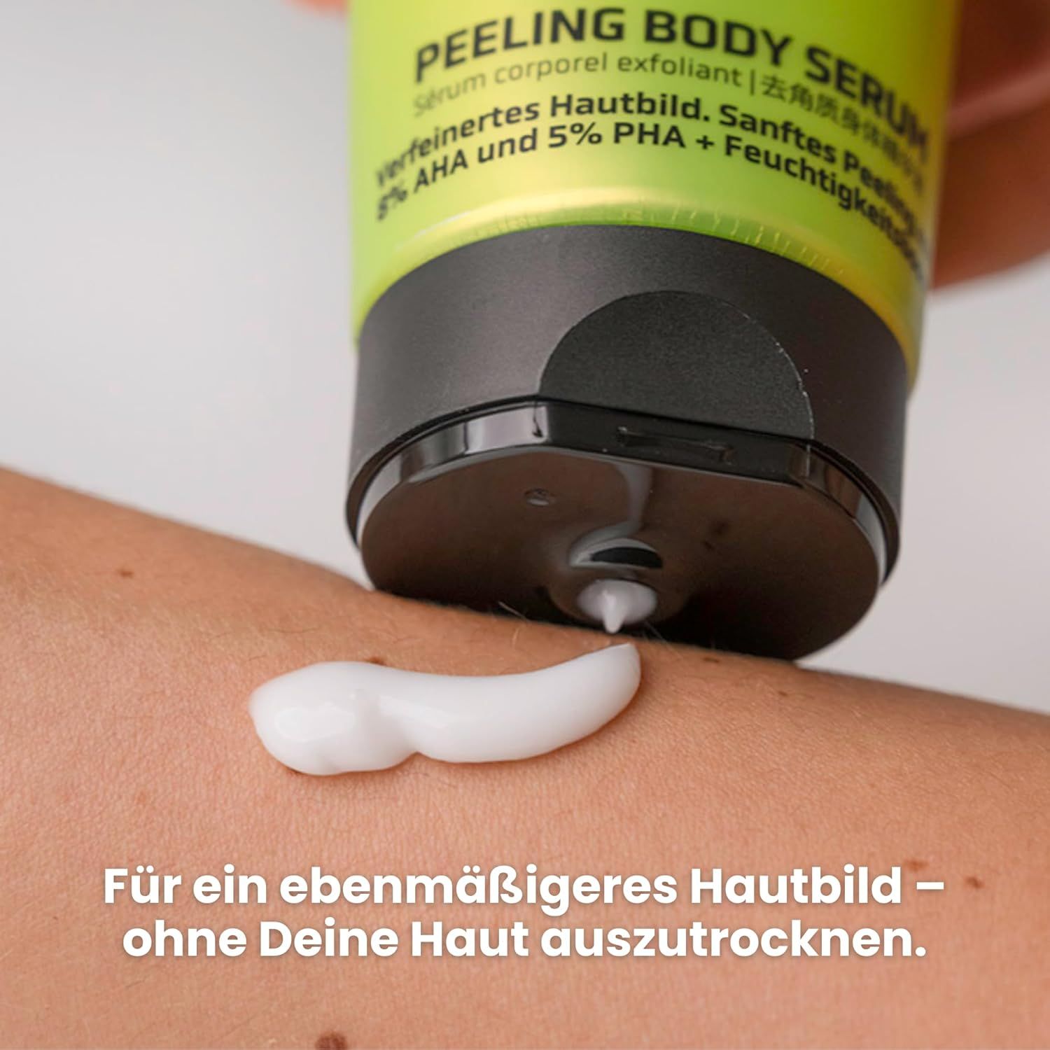 Helle Haut mit aufgetragener weißer Creme. Schwarzer Tubendeckel im Bild. Text: Peeling Body Serum. Creme wird aus der Tube gedrückt.