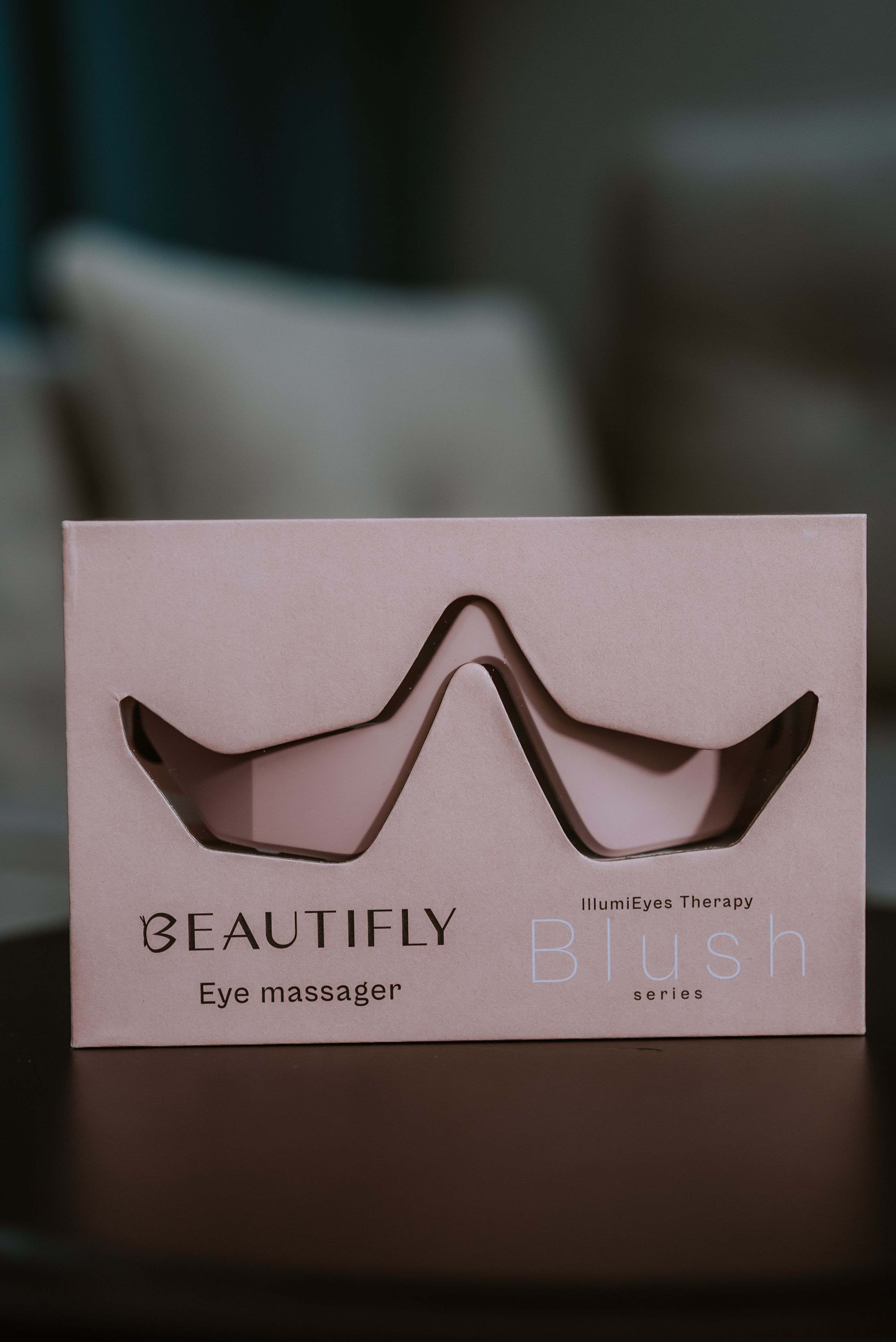Produktverpackung: Rosa Karton mit Aussparung für Augenmassagegerät. Aufdruck: BEAUTIFLY, IllumiEyes Therapy.