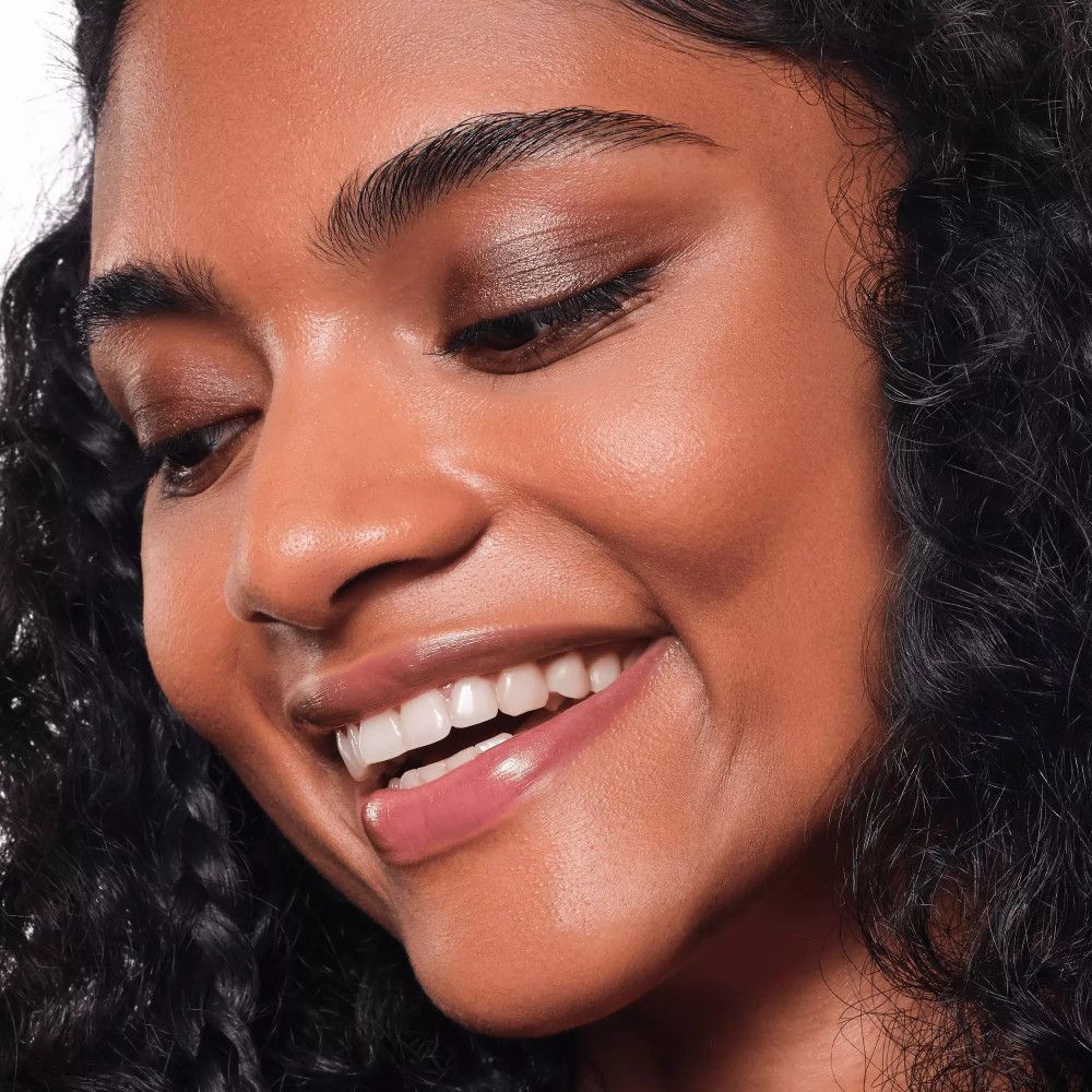 Porträt einer lächelnden Frau mit dunkler Haut und braunem Lidschatten.