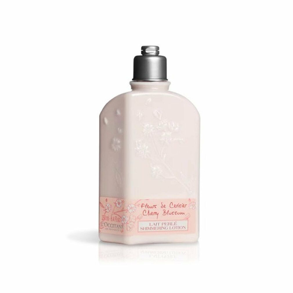 Beige Flasche mit Blütenrelief und silbernem Verschluss. Aufschrift: Fleur de Cerisier Cherry Blossom, Lait Perlé Shimmering Lotion.