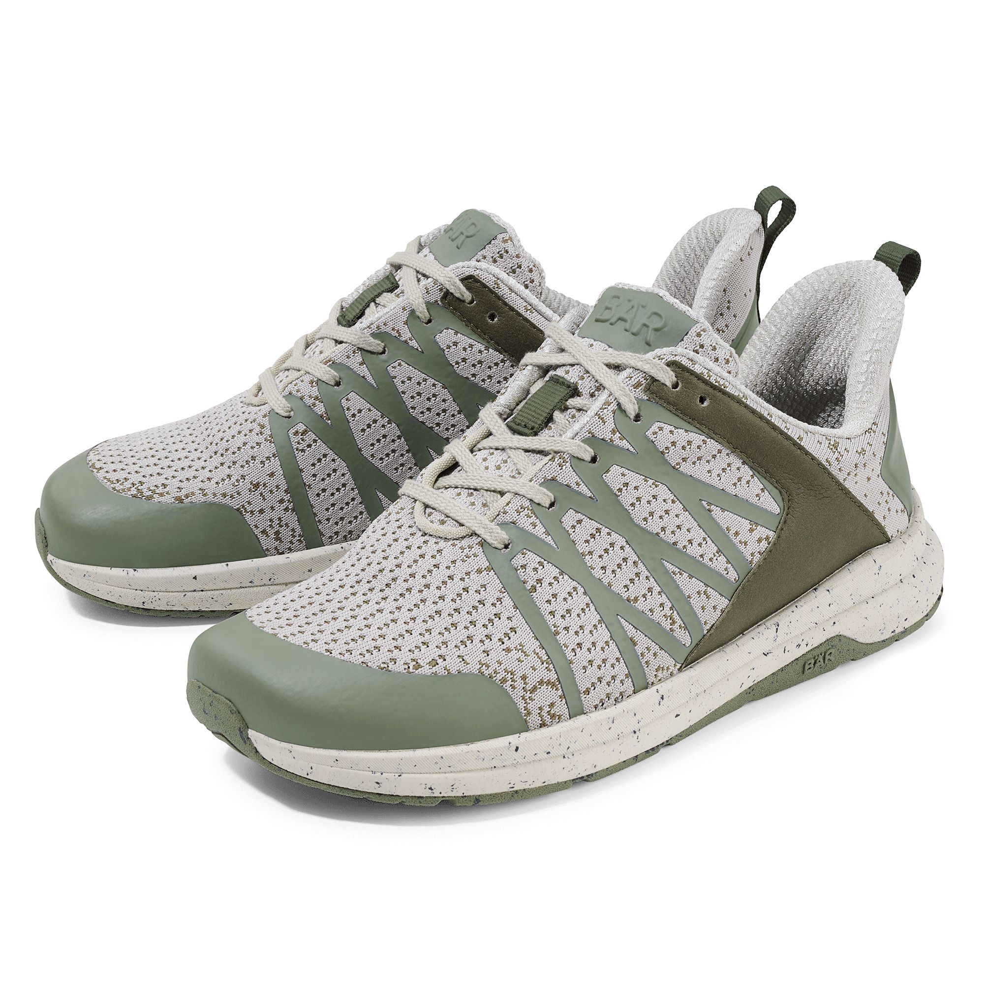 Zwei grüne und beige Schnürschuhe. Mesh-Obermaterial, grüne Akzente, weiße Sohle mit Flecken. BÄR-Logo.