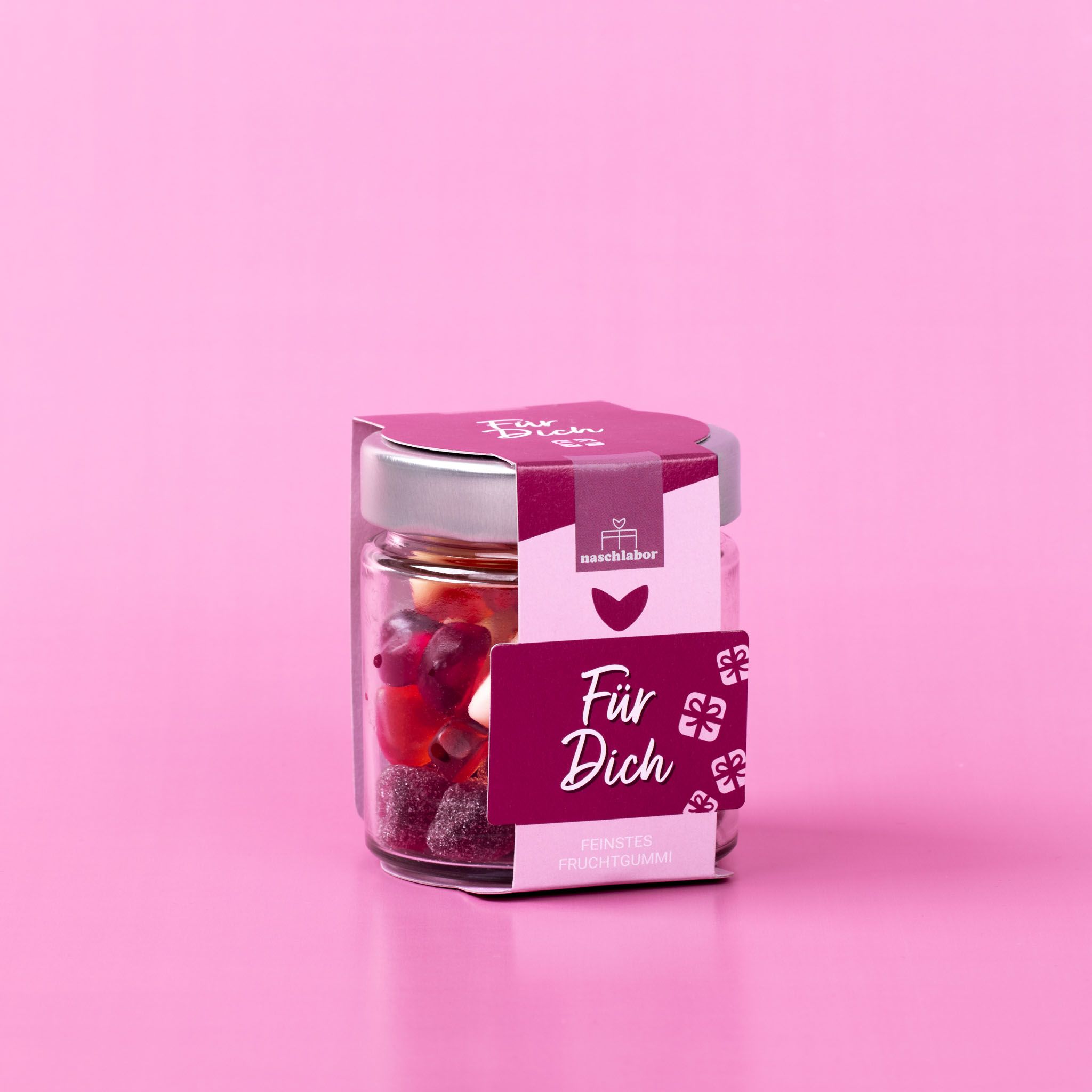 Glas mit Fruchtgummi, Etikett mit Schriftzug. Deckel silberfarben. Aufschrift: Für Dich, Feinstes Fruchtgummi. Hintergrund pink.
