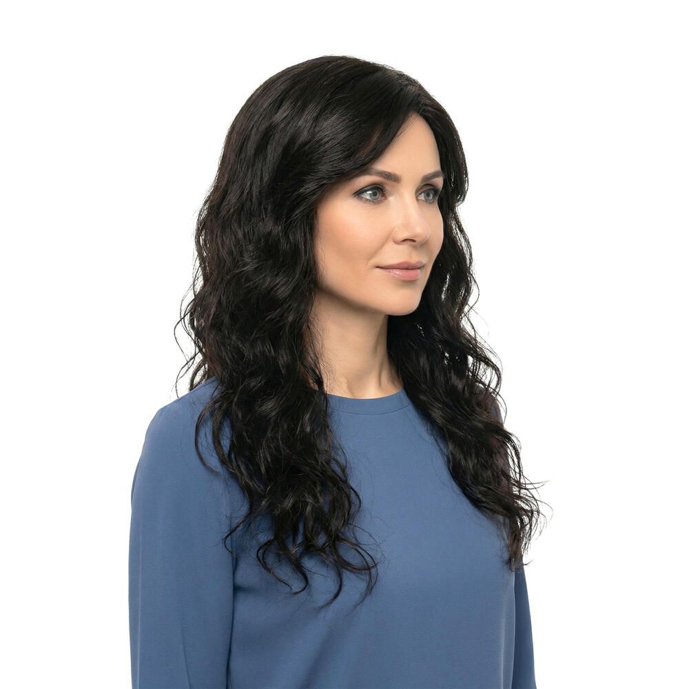 Dunkelbraune Perücke mit gewelltem Haar. Dreiviertelansicht einer Frau mit blauem Oberteil. Weißer Hintergrund.