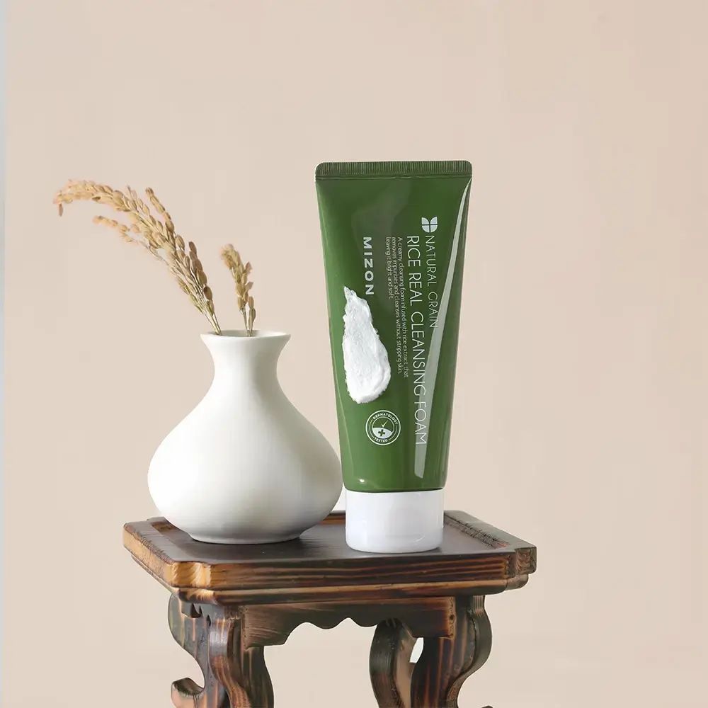 Grüne Tube mit weißem Verschluss. Schaum auf der Tube. Aufschrift: MIZON Rice Real Cleansing Foam. Produktname und Logo.