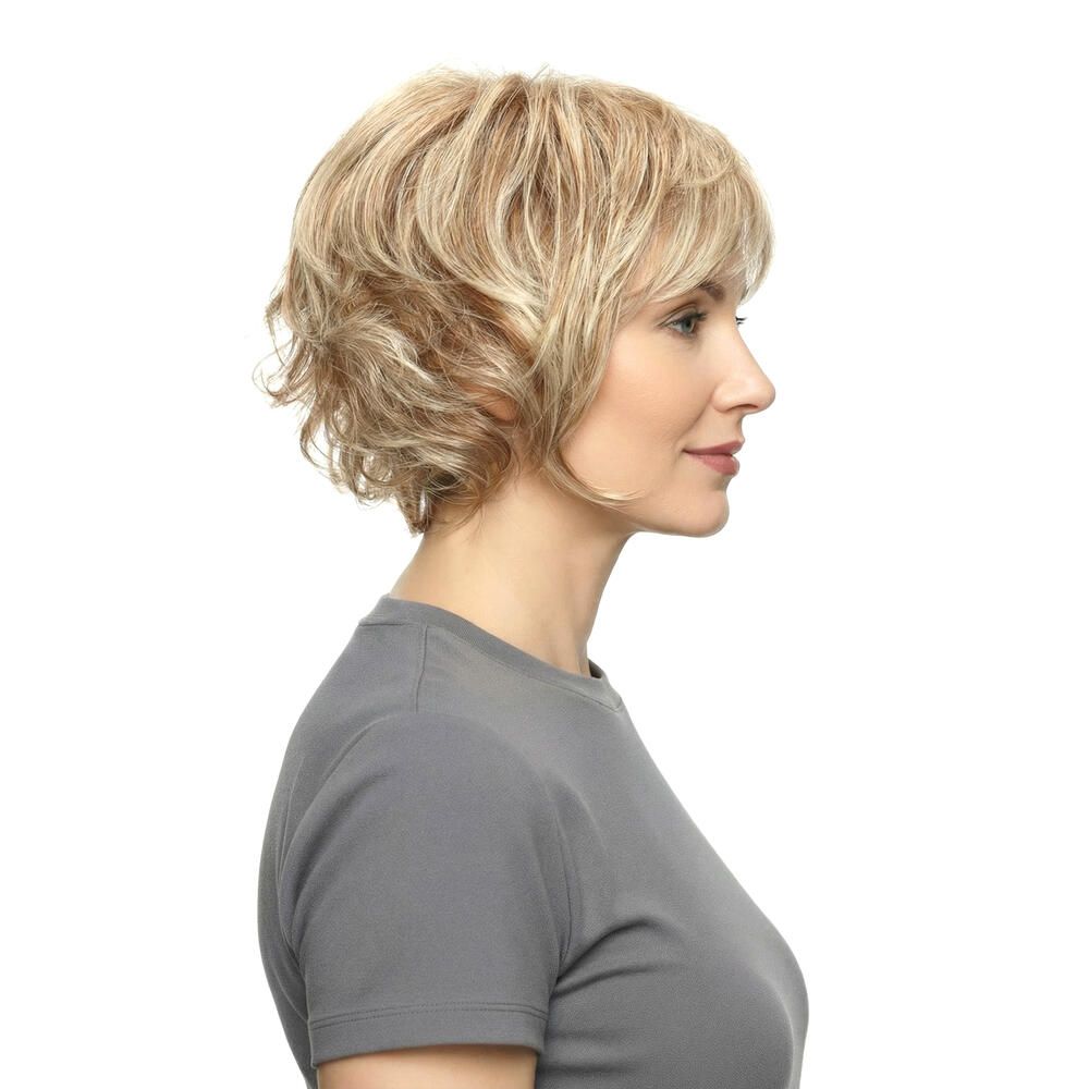 Blonde Perücke mit kurzem, gestuftem Schnitt. Die Frau trägt ein graues T-Shirt. Seitenansicht.