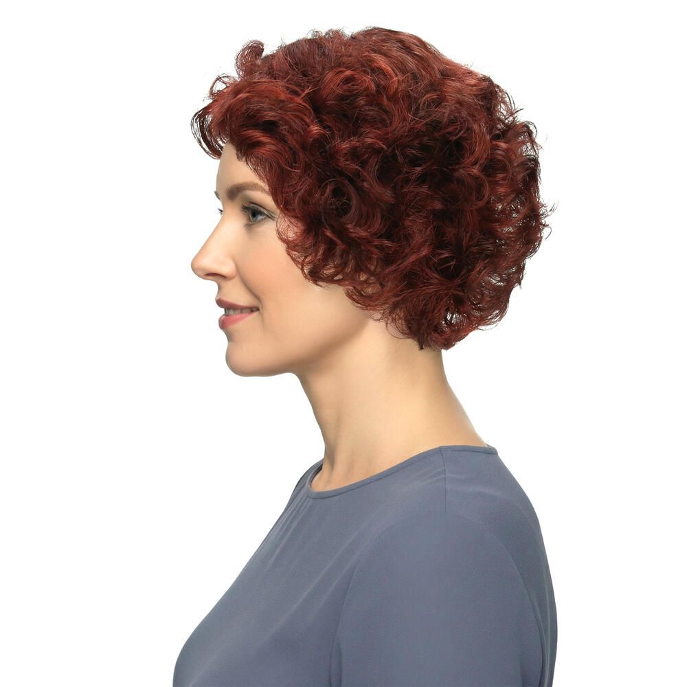 Profil einer Frau mit roter, lockiger Perücke. Kurzes, voluminöses Haar. Bluse in Blau. Weißer Hintergrund.