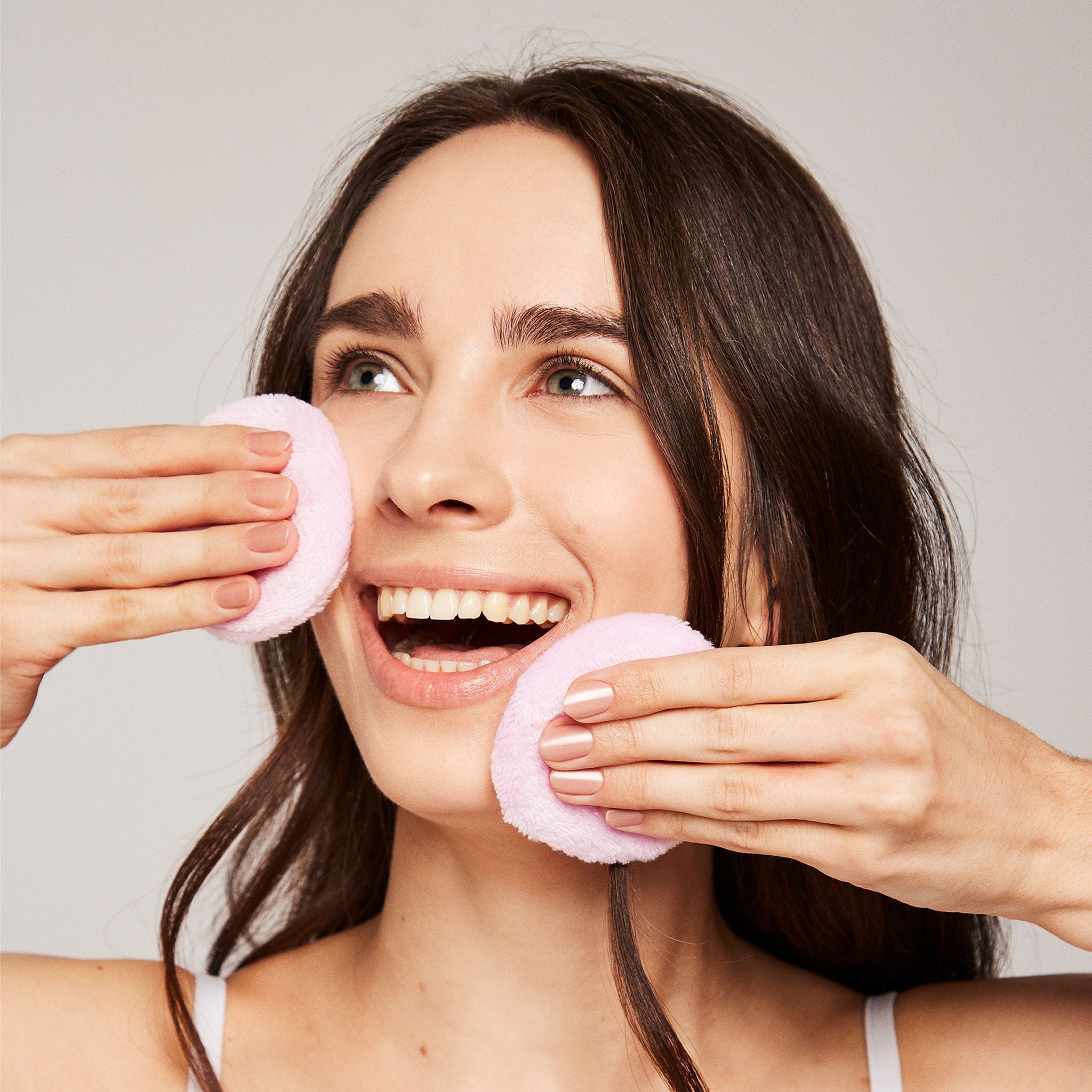 Frau mit zwei rosa Wattepads im Gesicht.