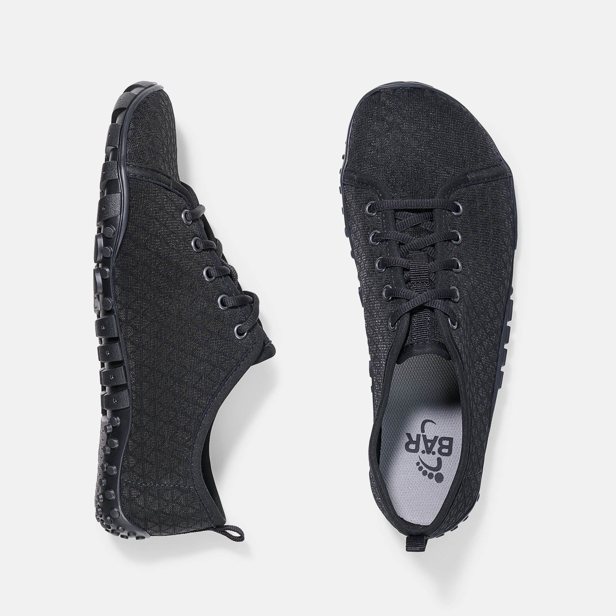 Zwei schwarze Schuhe. Obermaterial mit geometrischem Muster. Gummisohle. Schnürsenkel. Innensohle mit BAR-Logo.