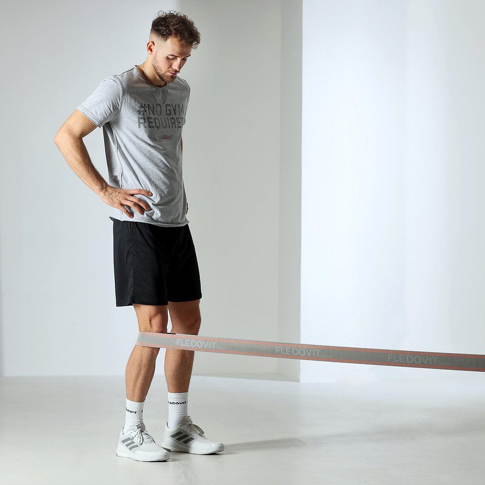 Mann trainiert mit FLEXVIT Resist Band. Das Band ist horizontal gespannt. Der Mann steht aufrecht.