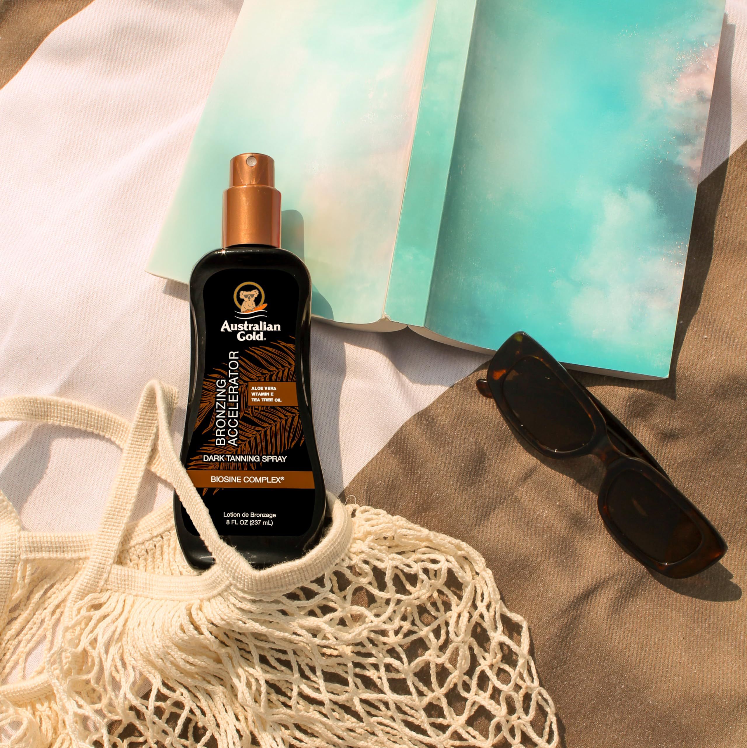 Spraygel mit Bronzer auf einem Strandtuch. Daneben Sonnenbrille und Notizbuch. Aufschrift: Australian Gold, Bronzing Accelerator.