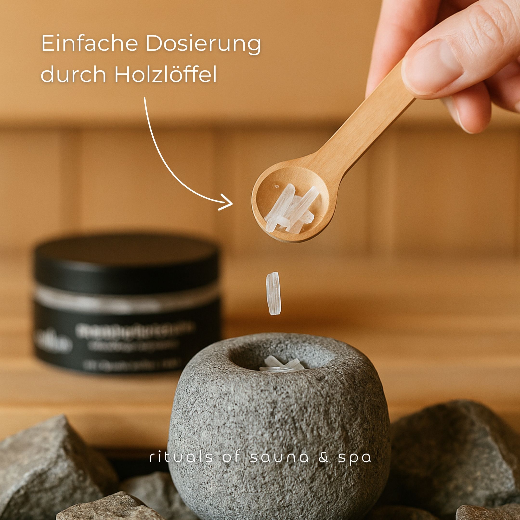Holzlöffel mit Mentholkristallen über Saunasteinen. Aufschrift: Einfache Dosierung durch Holzlöffel. Text: rituals of sauna & spa.