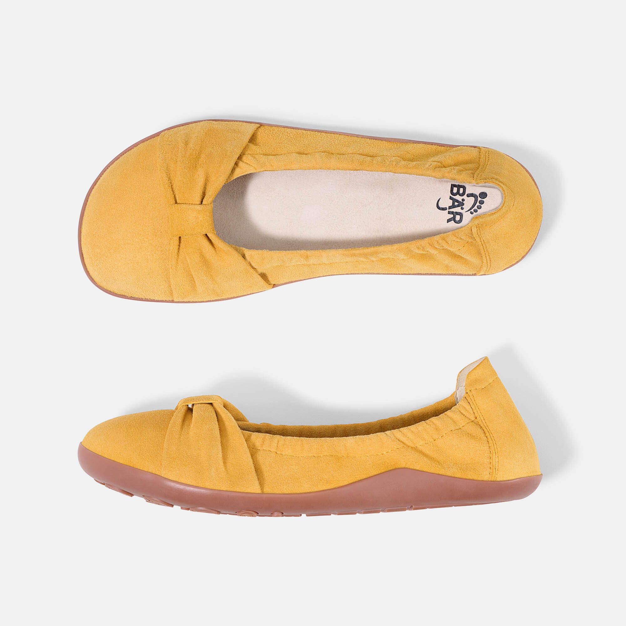 Gelbe Ballerinas. Wildleder, runde Zehen, Schleife vorne. Rosa Sohle. Marke BÄR. Zwei Schuhe nebeneinander.