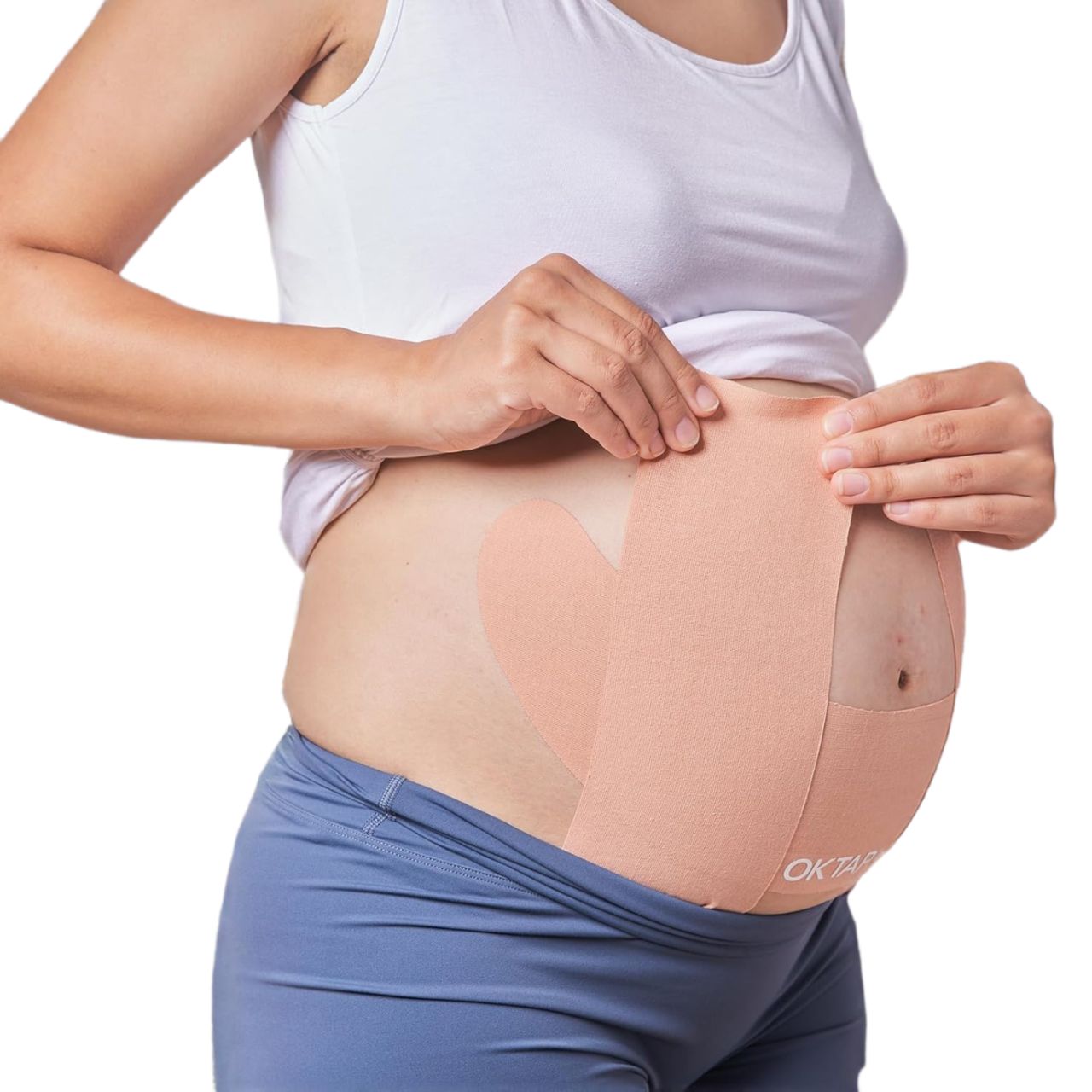 Hautfarbenes Kinesiologie-Tape, auf dem Bauch einer schwangeren Frau angebracht. Das Tape ist in Form von zwei Flügeln angebracht.