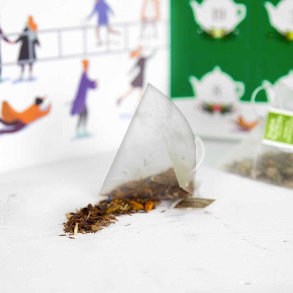 Offener Teebeutel mit losen Teeblättern. Hintergrund: Illustration des Adventskalenders mit Teekannen.