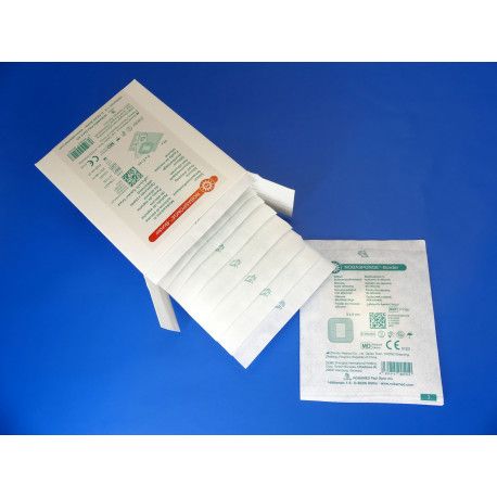 Packung mit einzelnen, verpackten Verbänden. Ein Verband ist aus der Packung entnommen und sichtbar. Verpackung mit Produktinformationen.