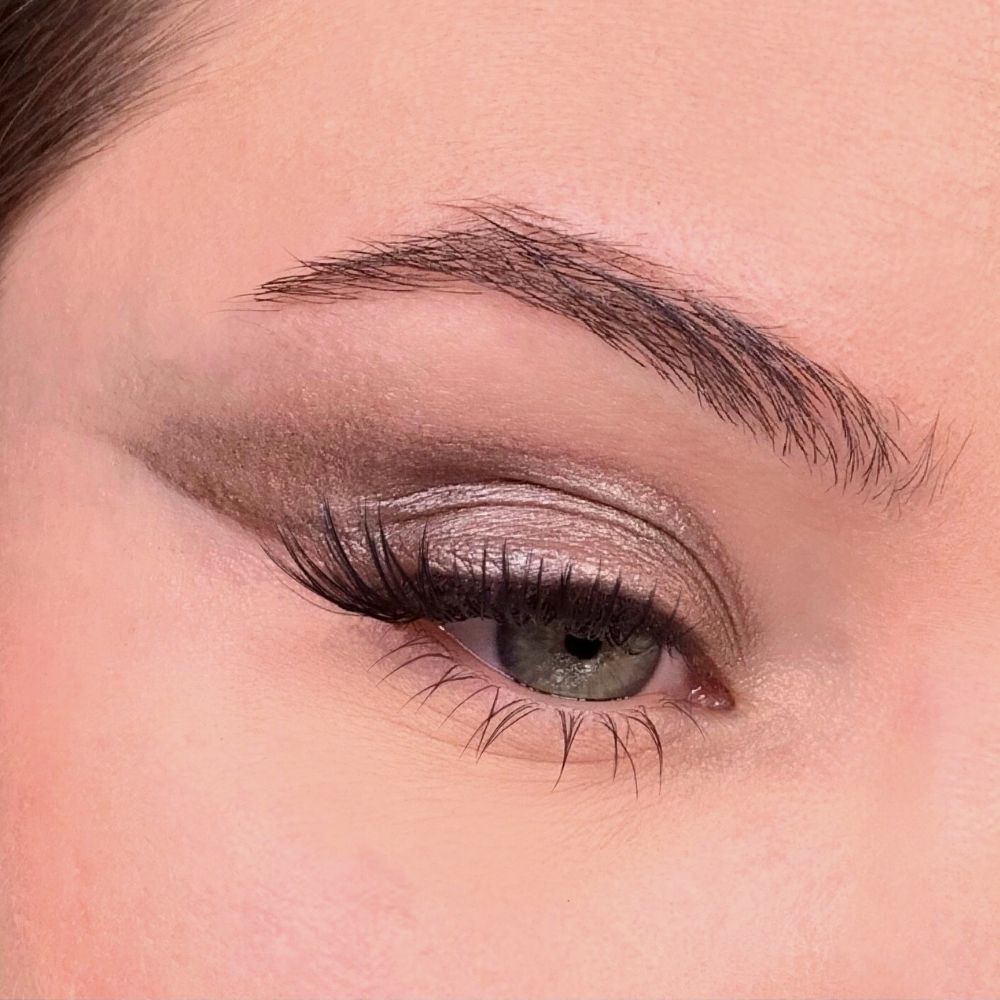 Auge mit Lidschatten. Das obere Augenlid ist mit Lidschatten bedeckt. Wimpern und Augenbrauen sind sichtbar.