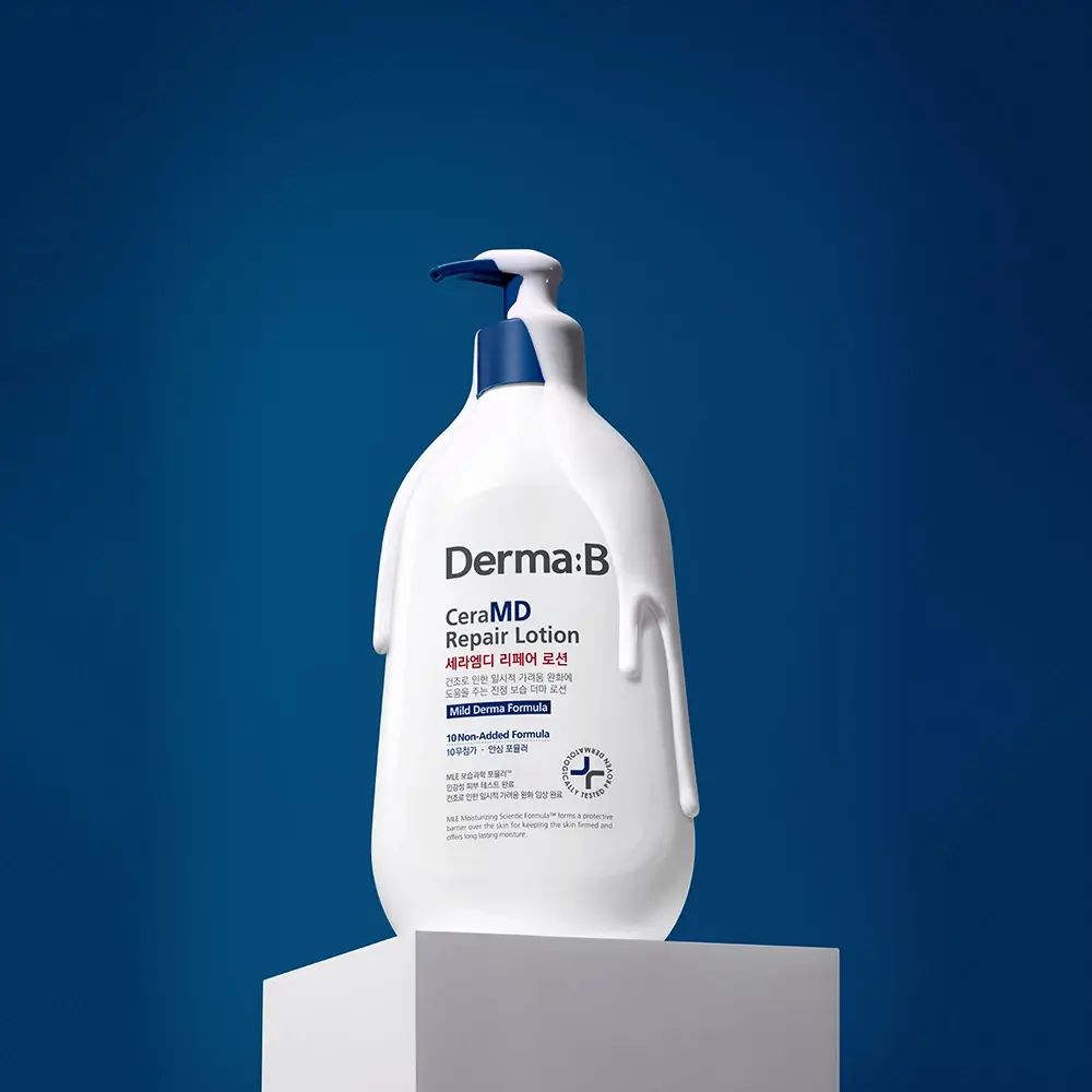 Weiße Flasche mit blauem Pumpkopf auf Sockel. Aufschrift: Derma:B CeraMD Repair Lotion. Creme läuft herunter.
