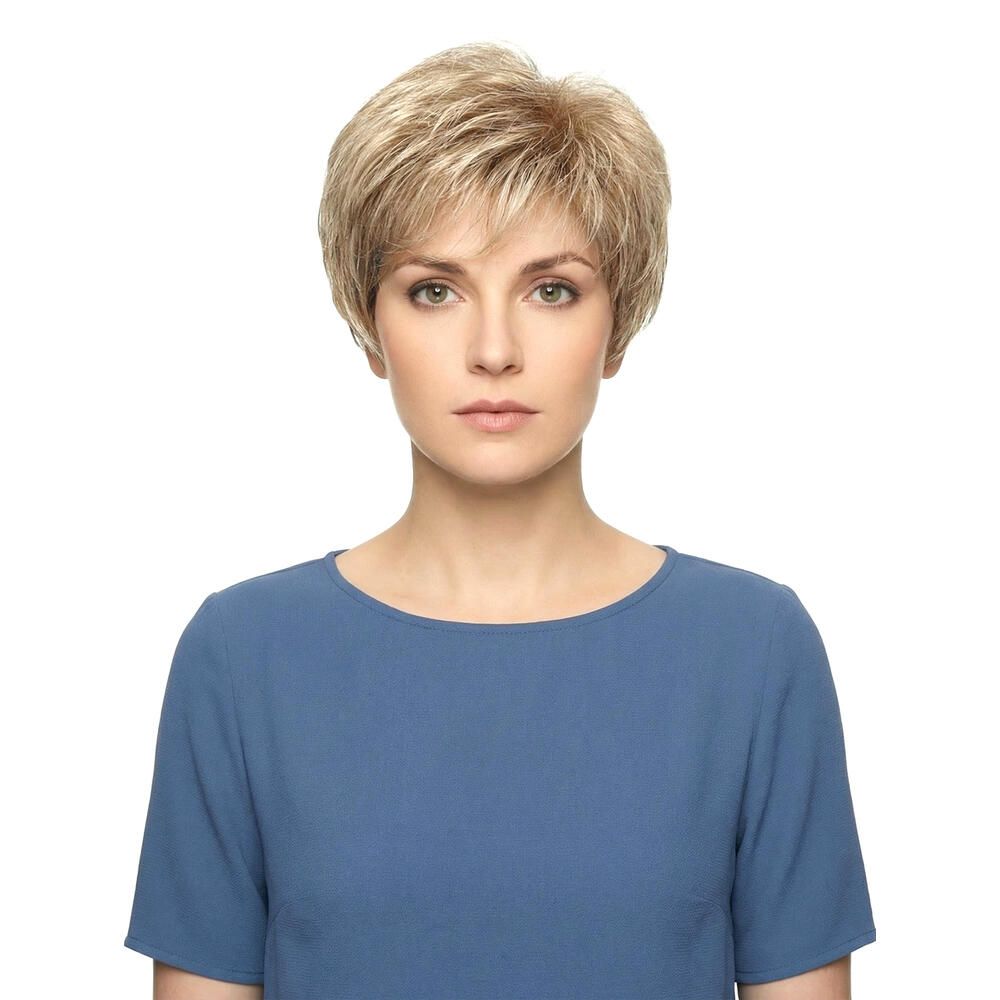 Kurzhaarperücke in Blondtönen. Frontale Ansicht einer Frau mit blauer Bluse. Die Perücke hat einen kurzen, fransigen Schnitt.