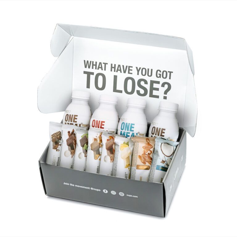 Geöffnete graue Schachtel mit Flaschen und Riegeln. Auf der Schachtel steht: „WHAT HAVE YOU GOT TO LOSE?“ Die Flaschen tragen die Aufschrift „ONE“. Riegel mit verschiedenen Aufdrucken.