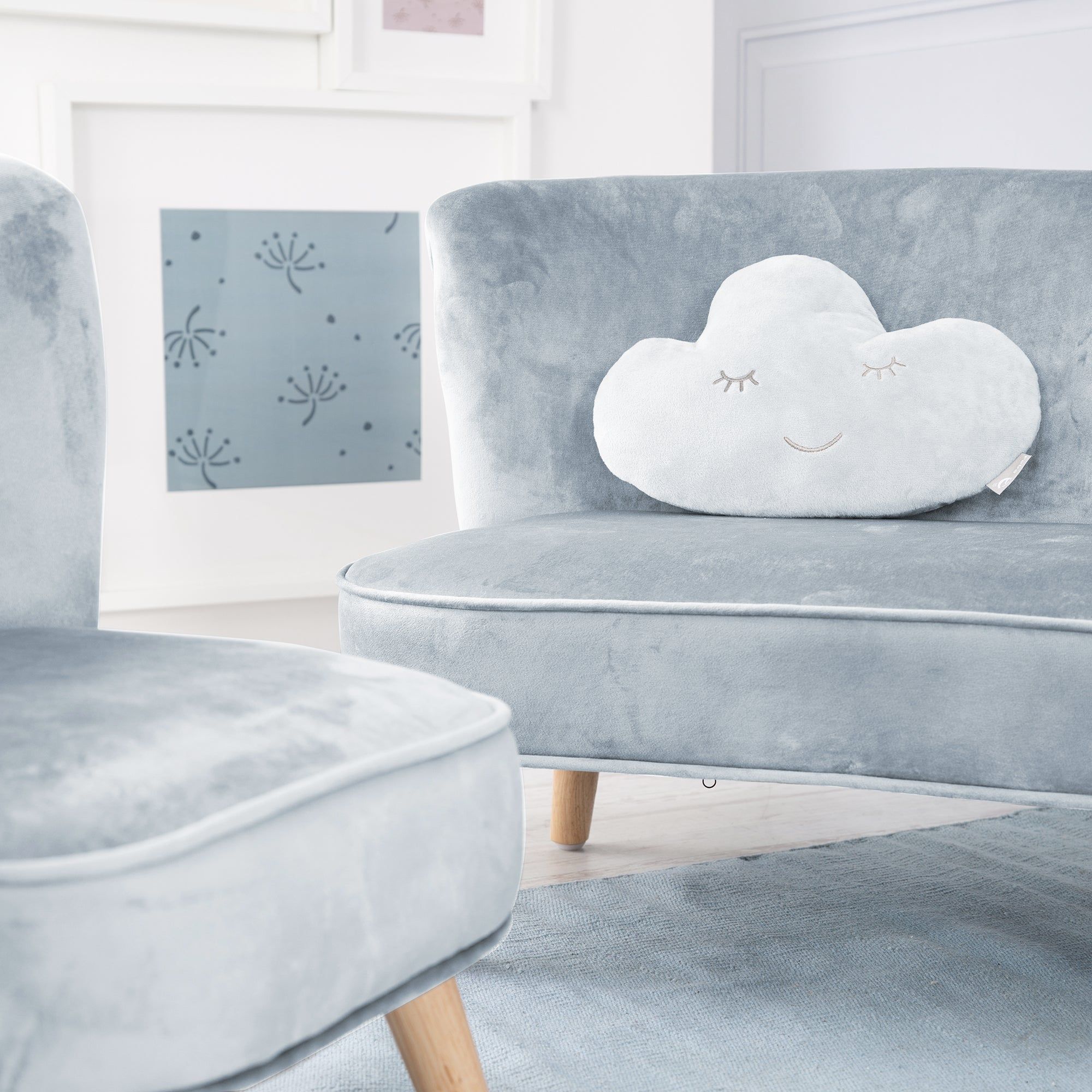 Weißes Wolkenkissen mit geschlossenen Augen und Lächeln auf einem blauen Sessel. Im Hintergrund ein weiterer Sessel.