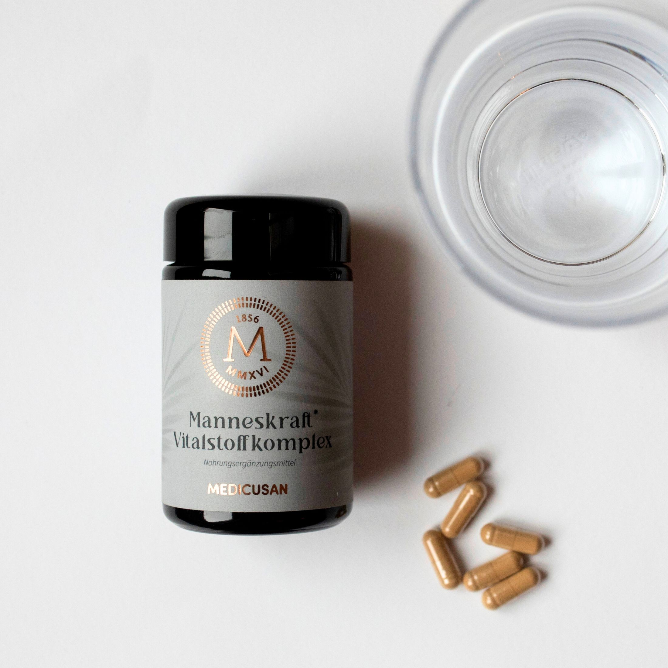 Dose "Manneskraft Vitalstoffkomplex" neben Glas Wasser und Kapseln. MEDICUSAN-Logo. Nahrungsergänzungsmittel.