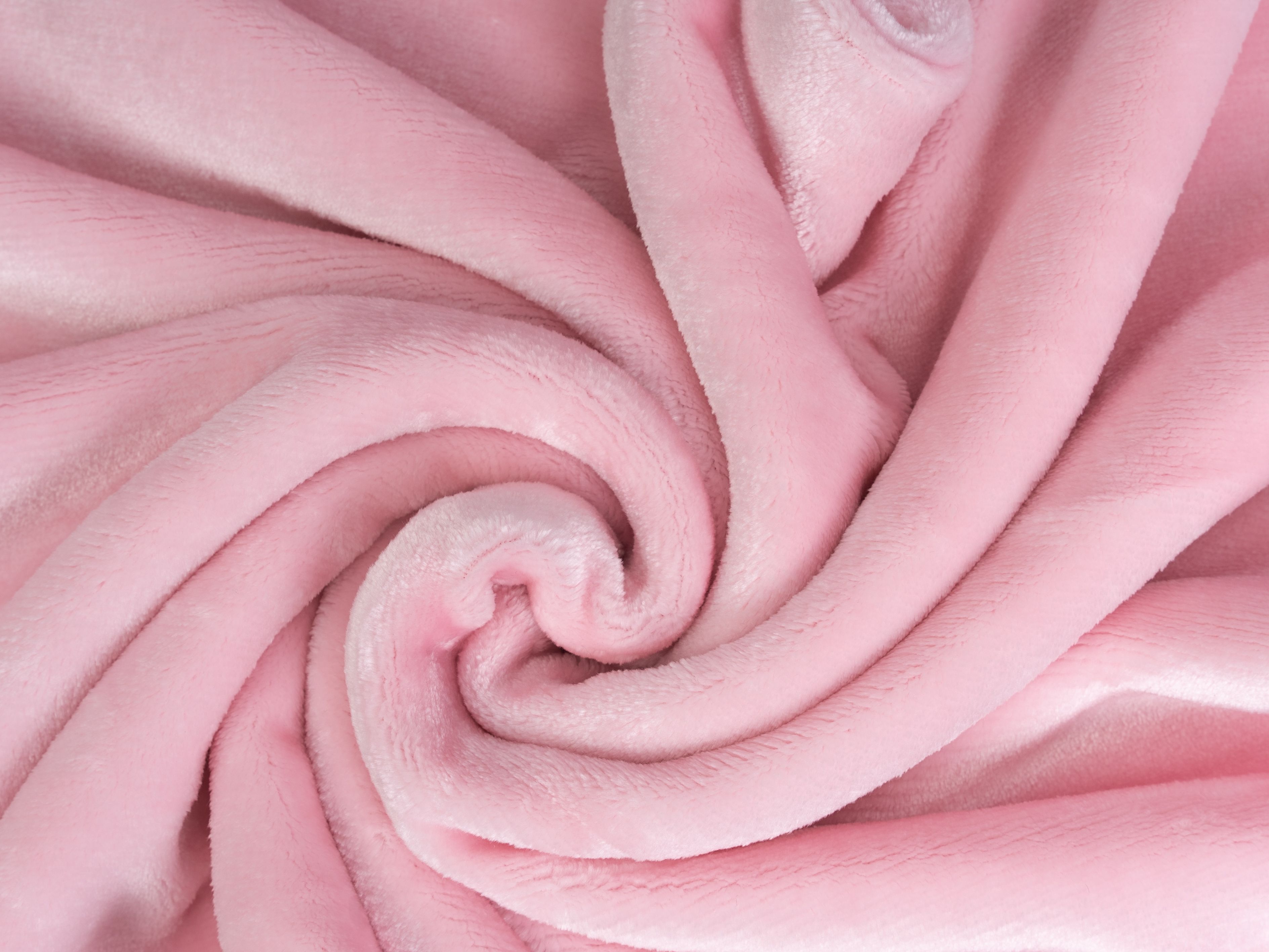 Rosa Kuscheldecke, gerollt. Weiches Material, wellenförmige Struktur. Detailaufnahme.
