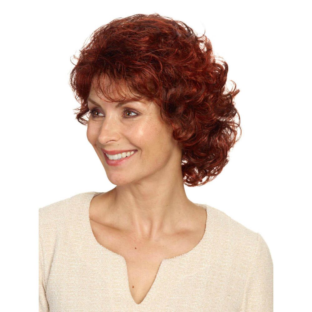 Frau mit roter, lockiger Perücke. Sie trägt ein cremefarbenes Oberteil und lächelt.