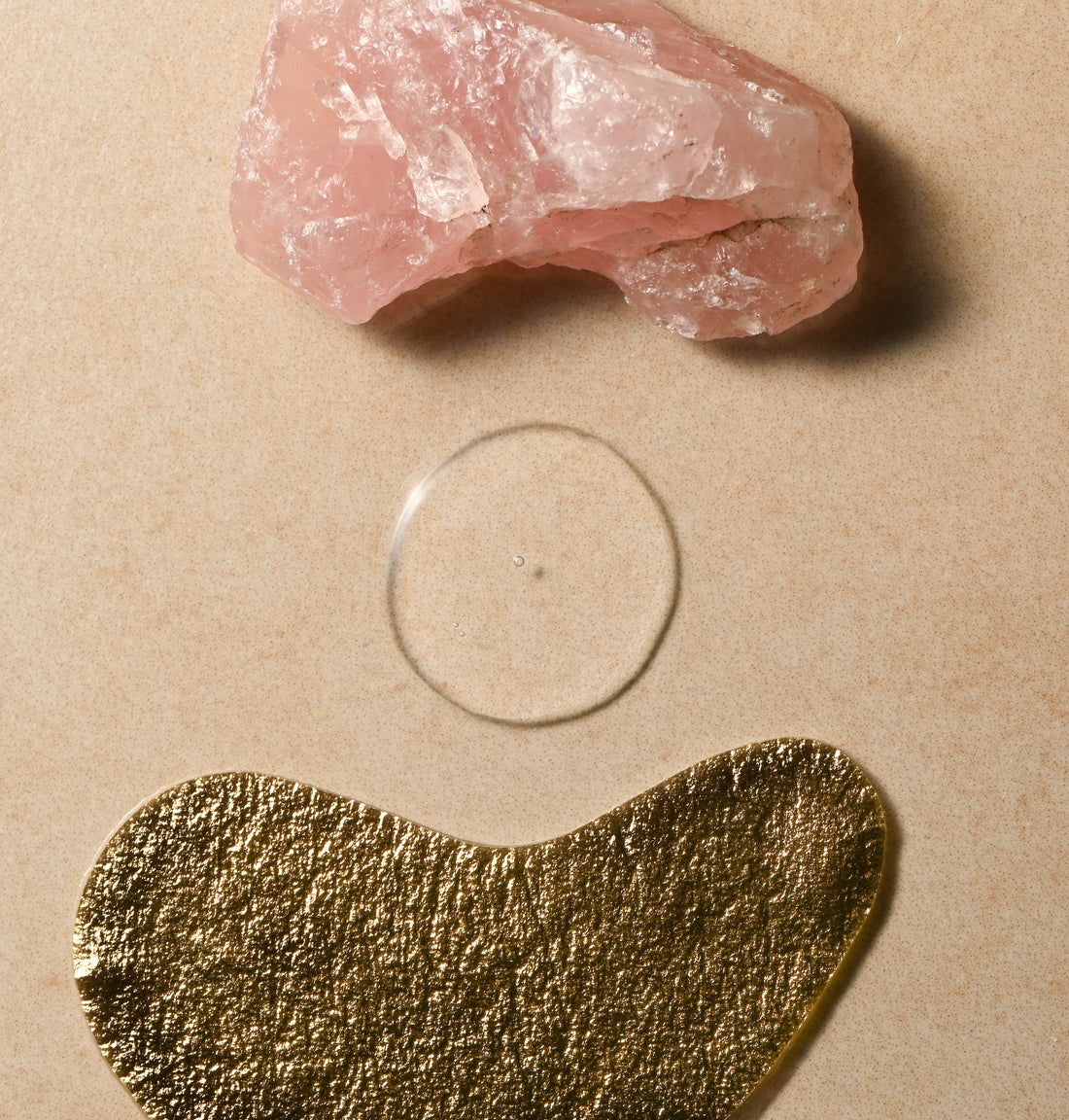 Drei Objekte: ein rosa Stein, ein durchsichtiges rundes Objekt und ein goldfarbenes, unregelmäßig geformtes Objekt.
