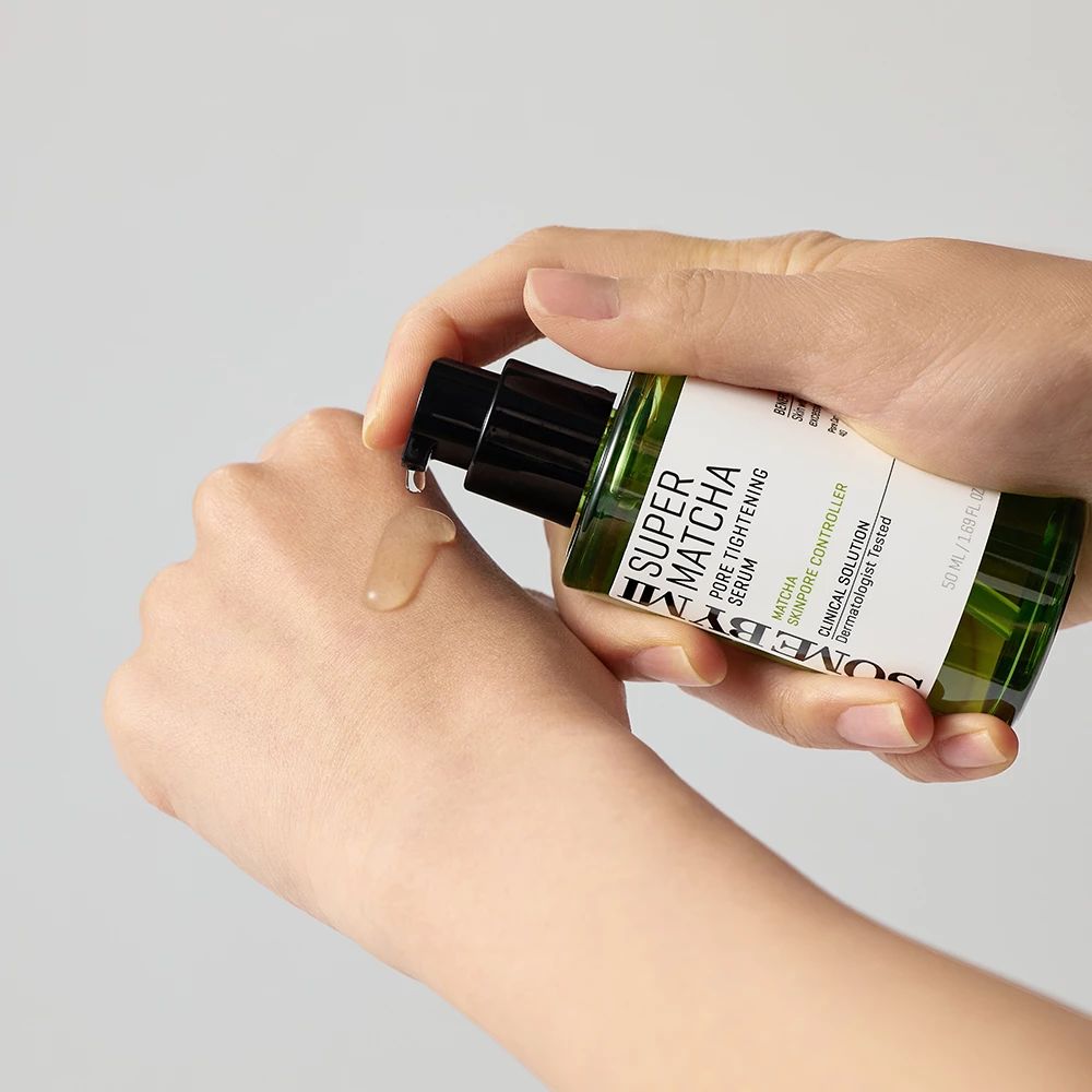 Grünes Serumfläschchen mit schwarzem Pumpkopf. Produkt wird auf die Hand aufgetragen. Text: Super Matcha Pore Tightening Serum.