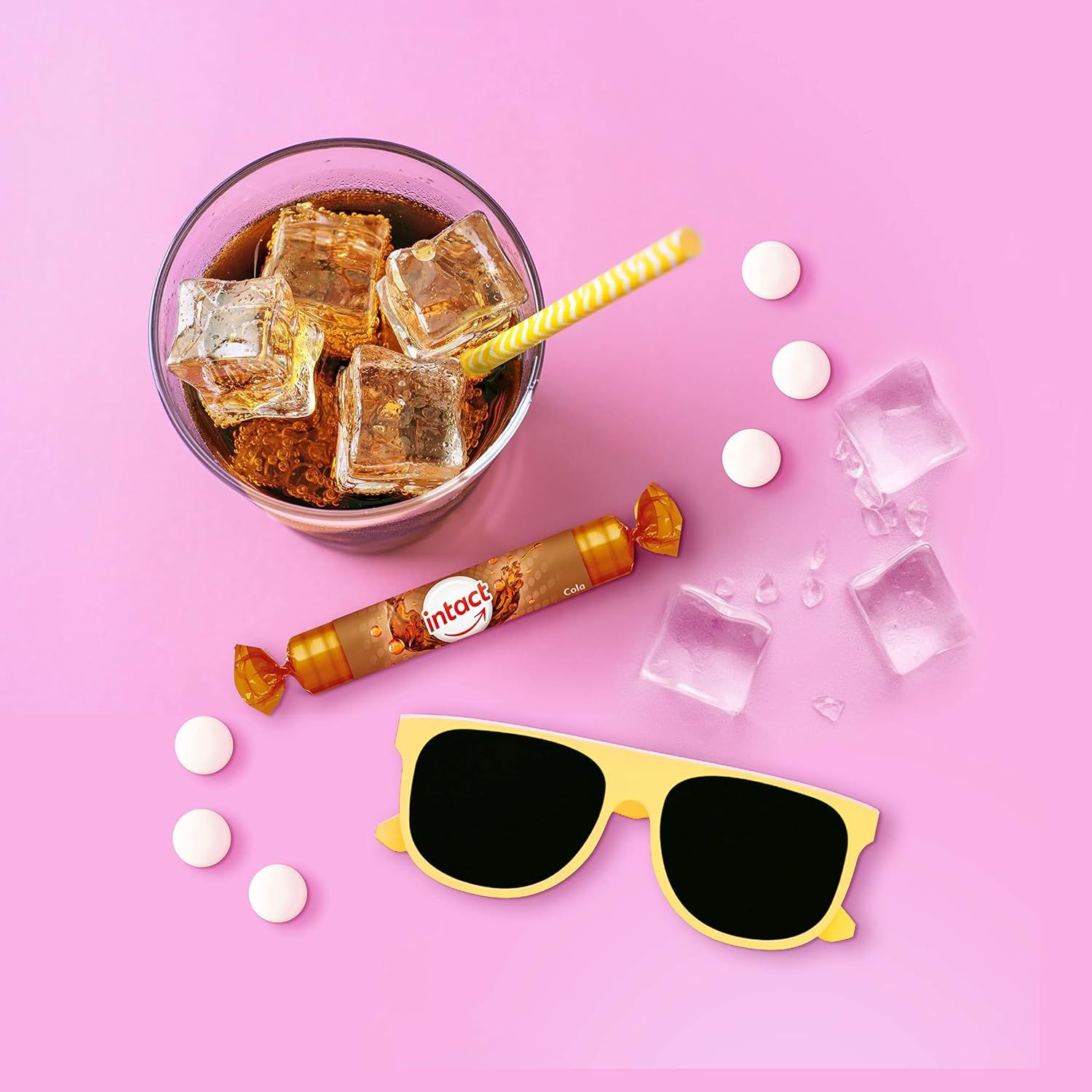 Glas mit Eiswürfeln und Getränk, daneben eine Rolle Traubenzucker, Tabletten, Sonnenbrille. Aufschrift: intact.