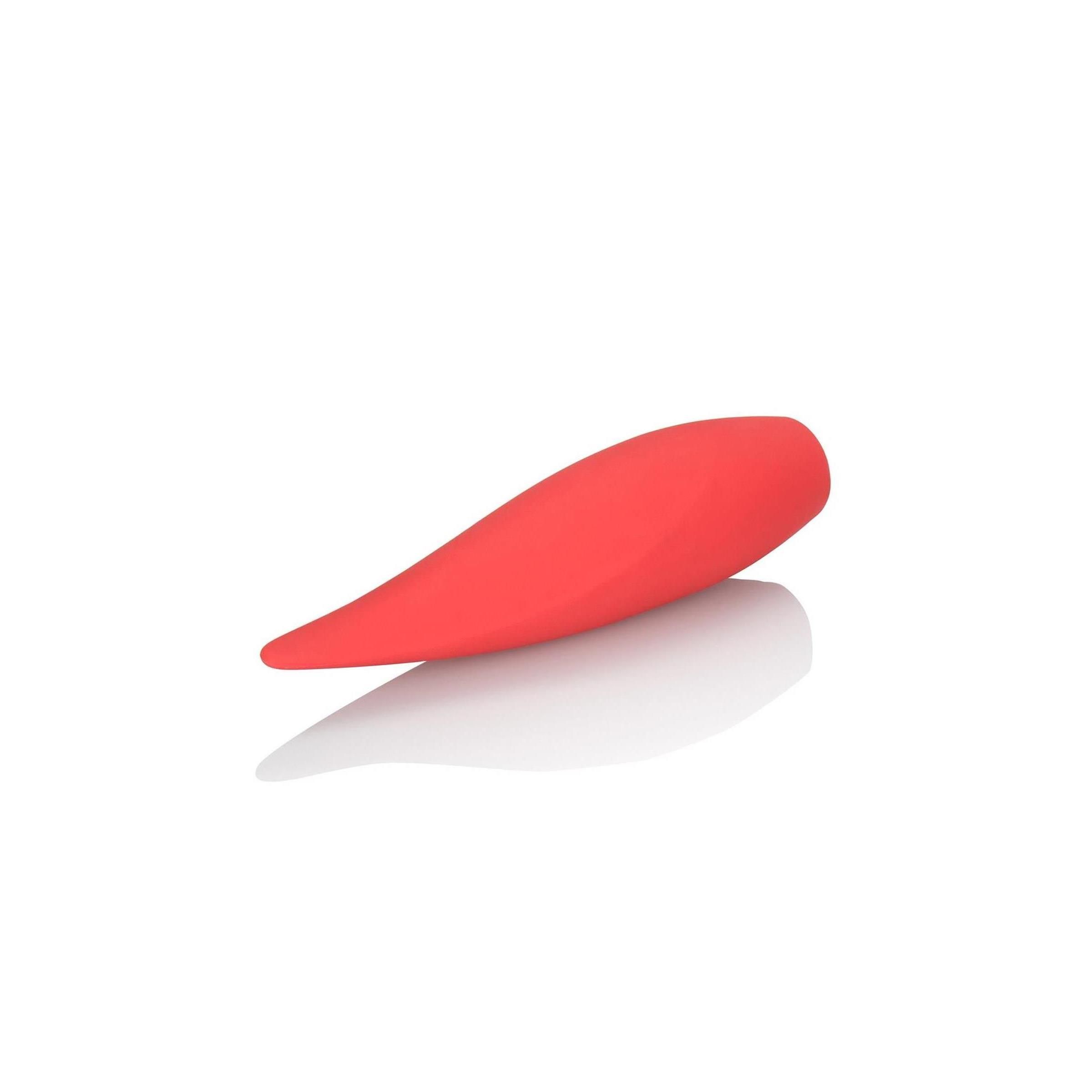Rotes, tropfenförmiges Wellness-Produkt. Glatte Oberfläche, leicht gebogen. Liegt auf einer reflektierenden Oberfläche.
